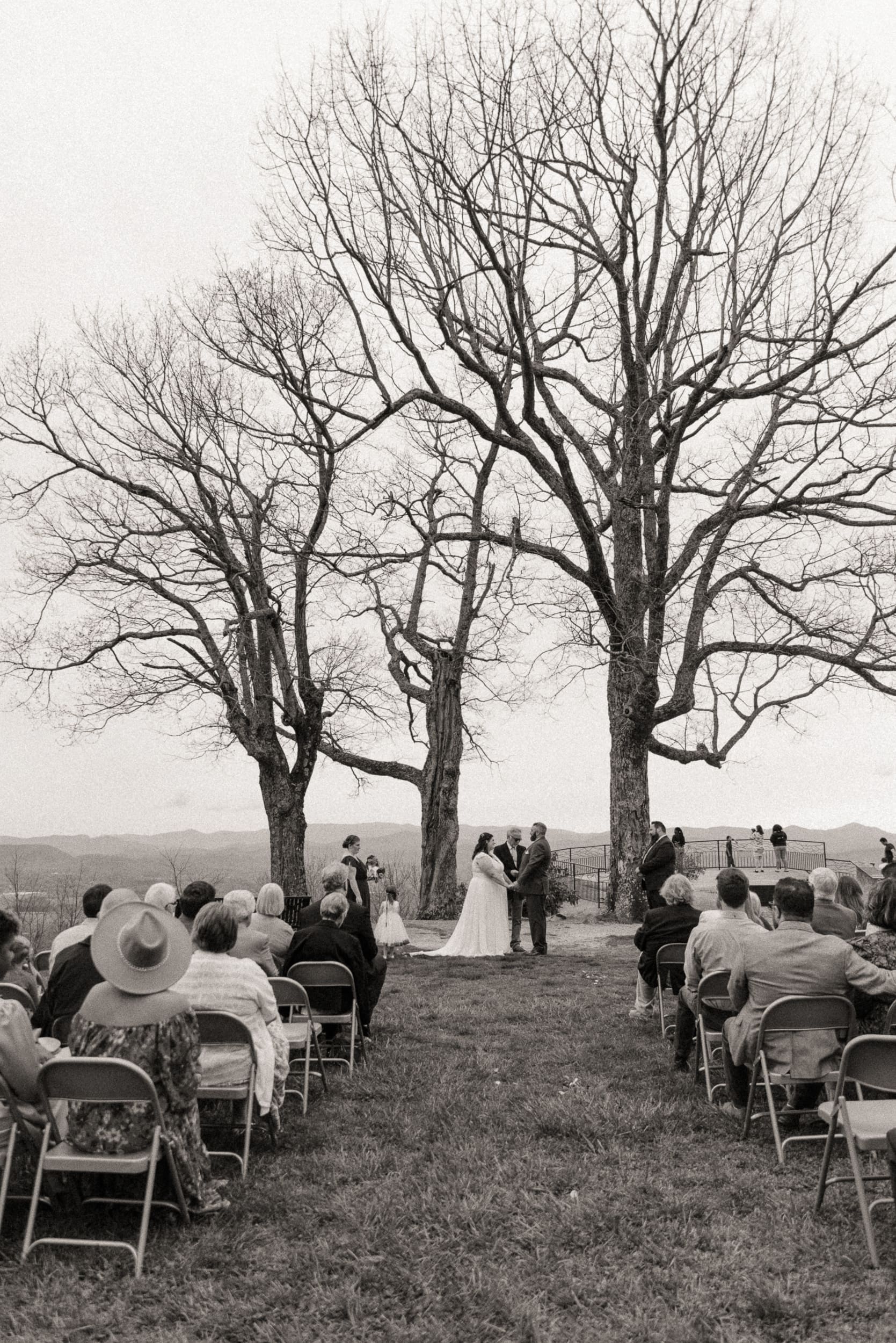 Black and white photo of intimate mountain wedding ceremony with guests seated outdoors