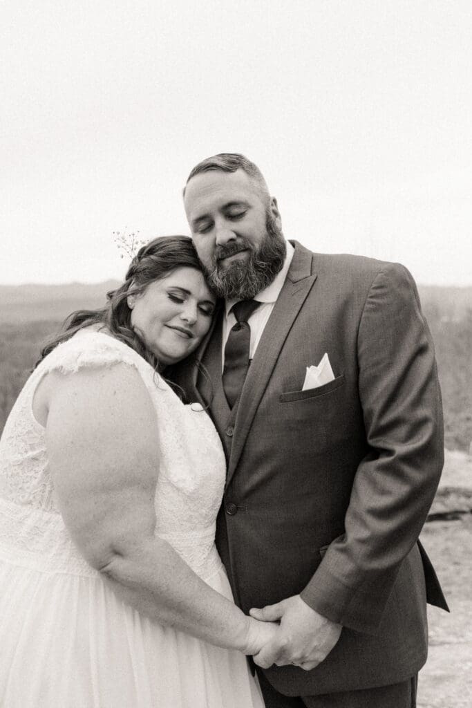 Black and white portrait of bride and groom embracing during intimate mountain wedding