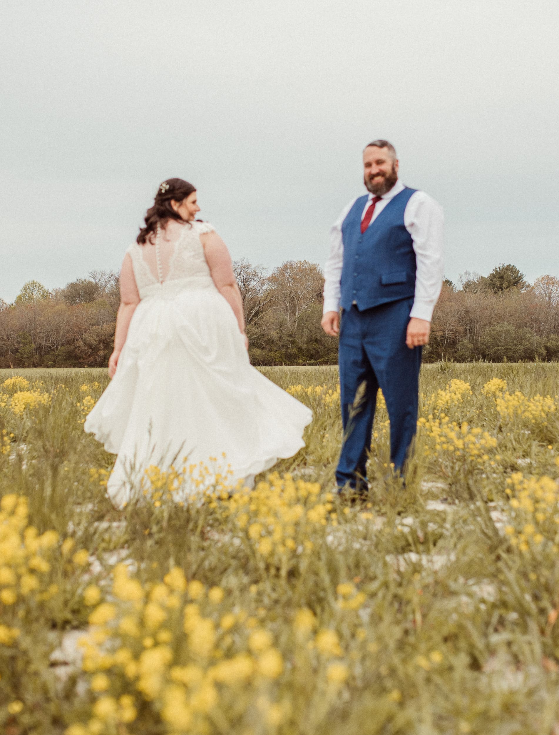 Bride twirling dress while groom smiles during candid mountain wedding portrait session