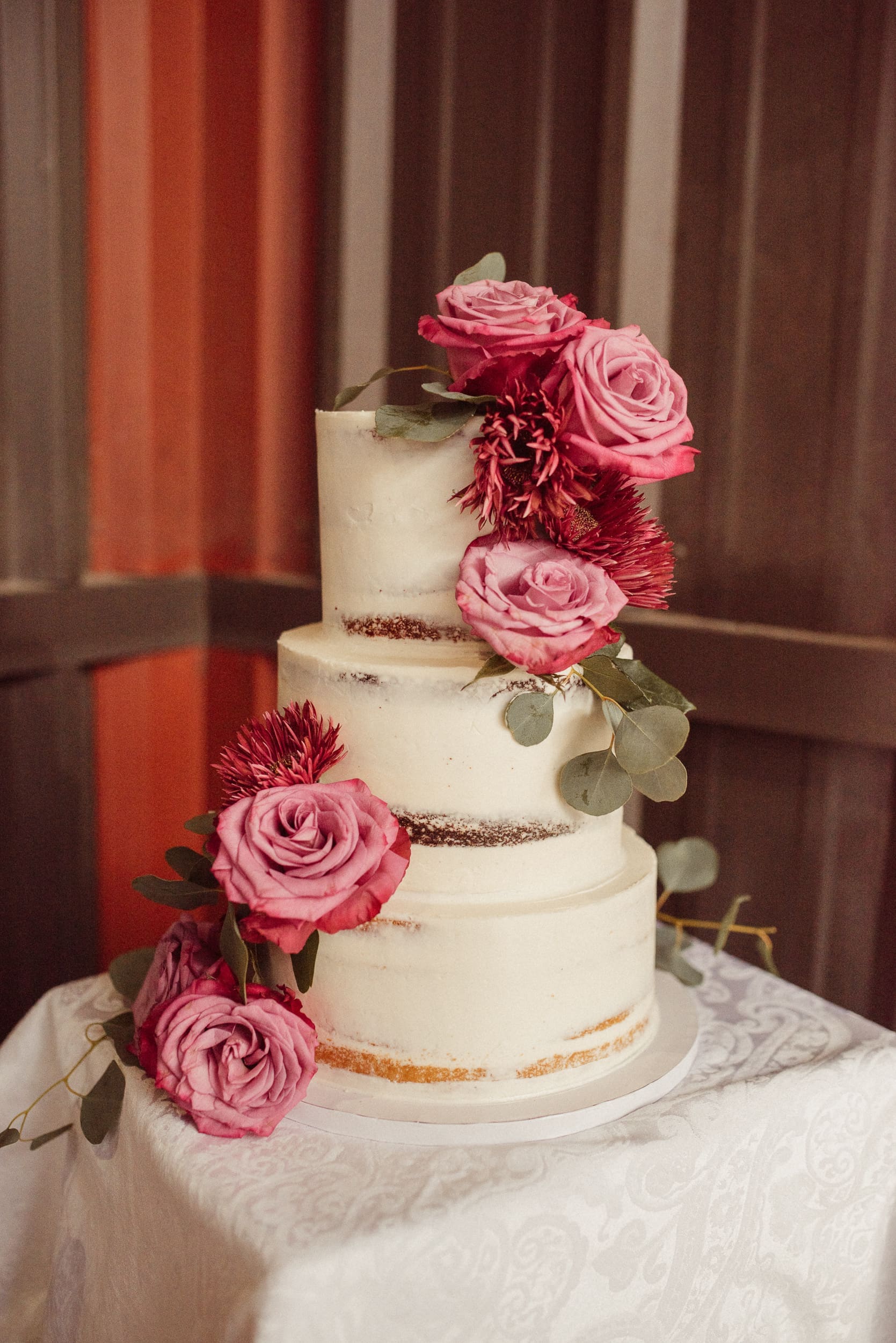 Small wedding cake decorated with pink flowers at intimate wedding reception