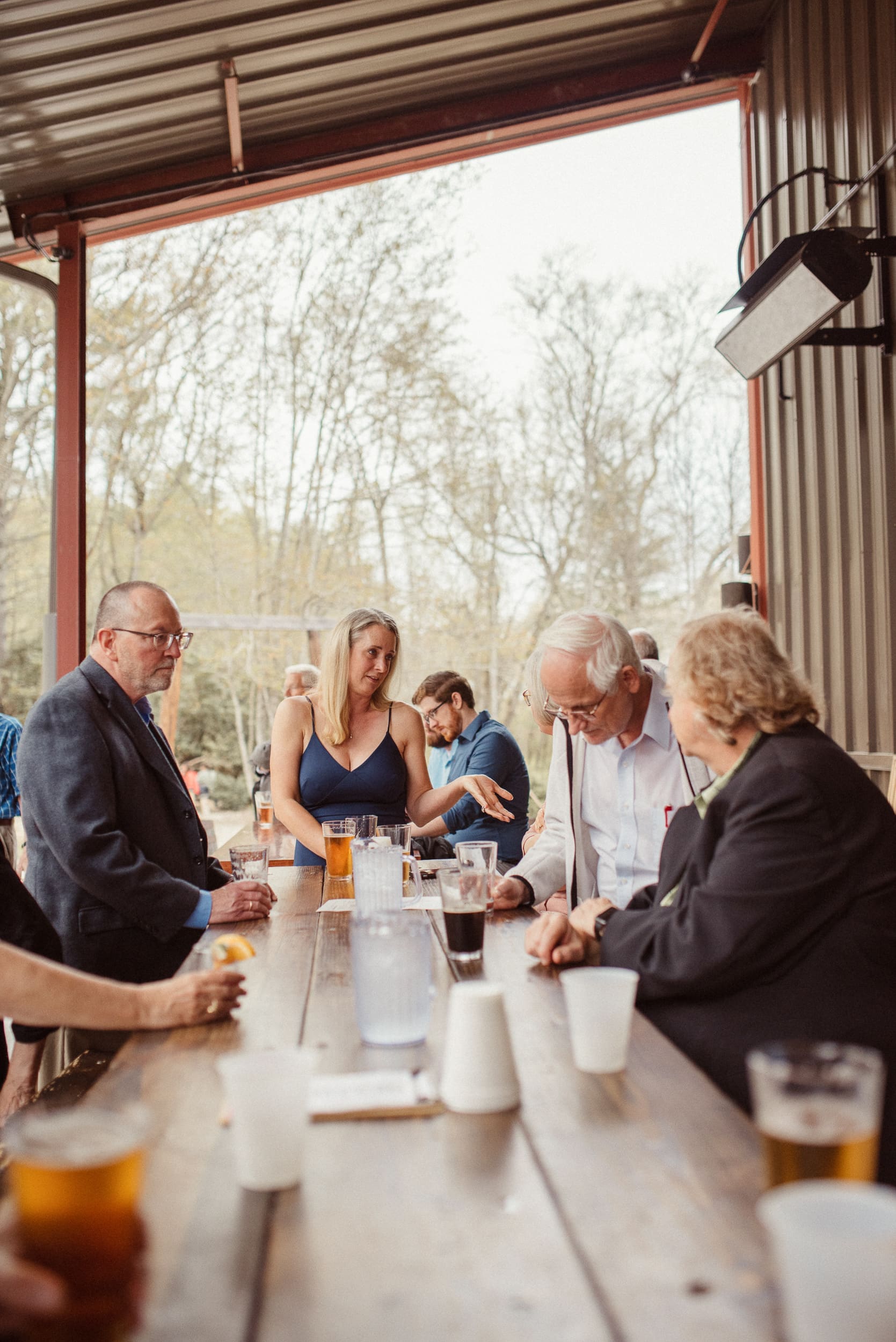 Wedding guests gathered around table during relaxed brewery reception after ceremony