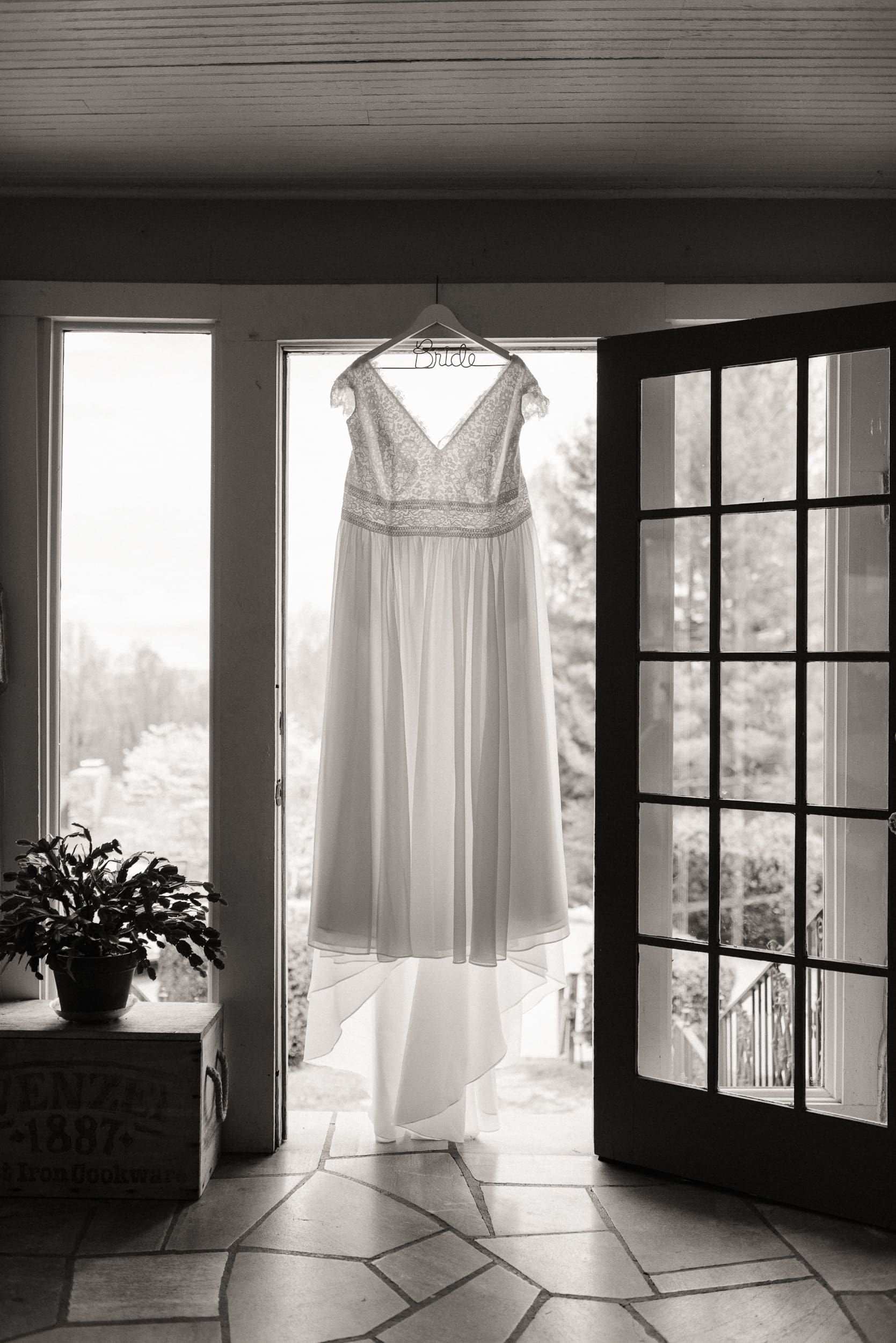 Wedding dress hanging in soft window light before an intimate mountain wedding in North Carolina.