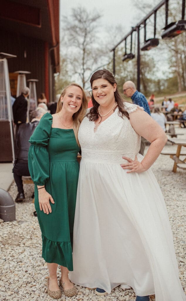 Bride posing with friend during relaxed wedding reception at outdoor brewery