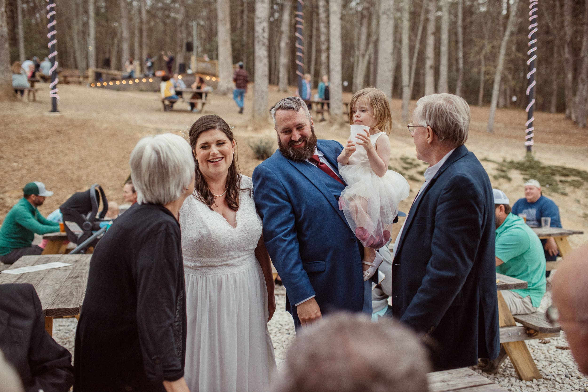 Bride and groom smiling with child during candid family moment at wedding reception