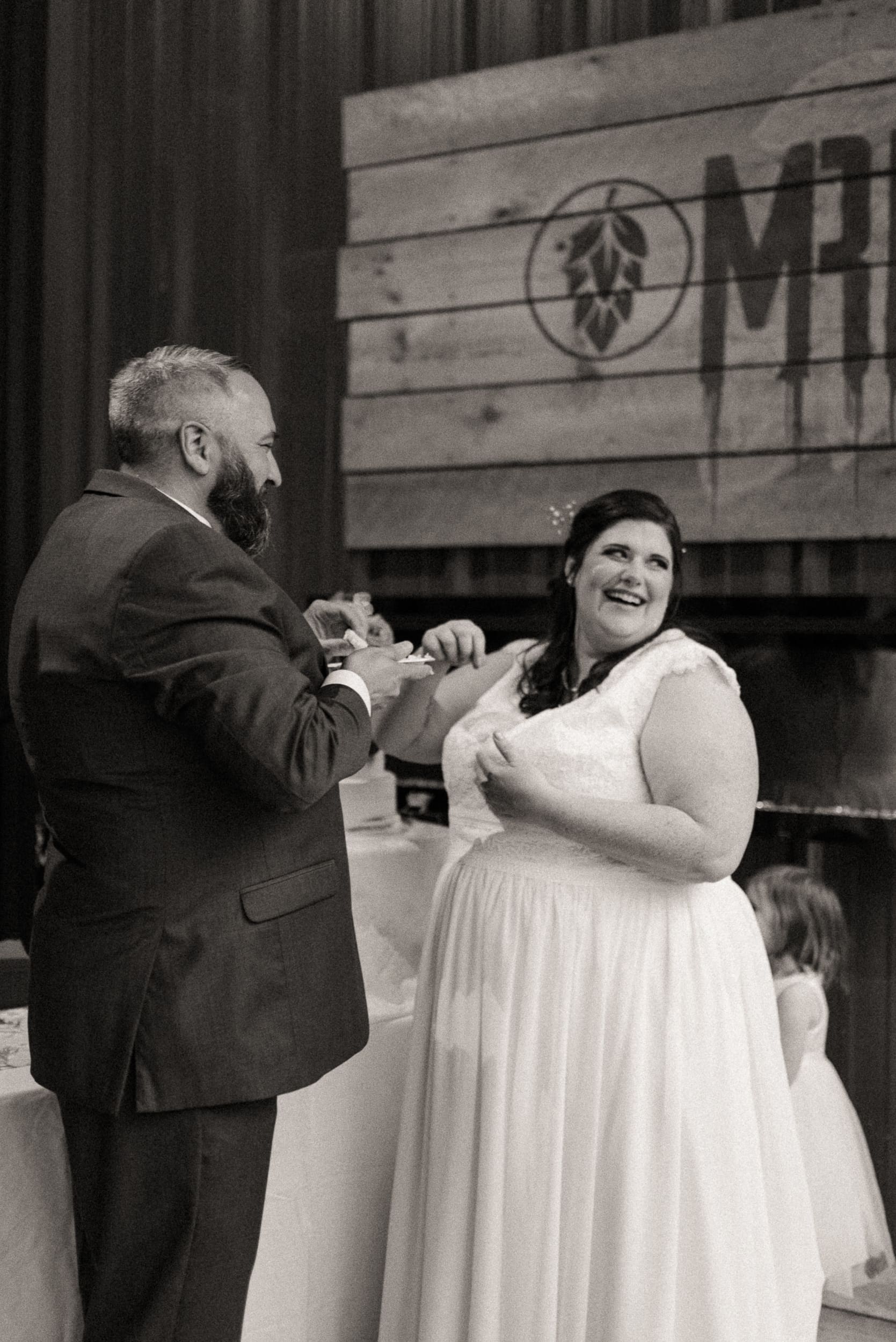 Bride and groom laughing during cake cutting at intimate wedding reception