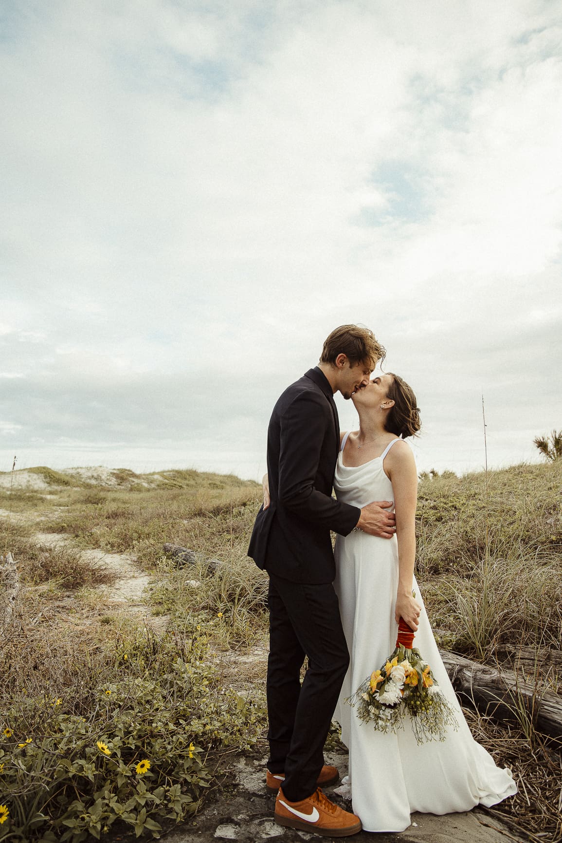 Romantic St. Augustine wedding portrait of a couple kissing in coastal dunes. 