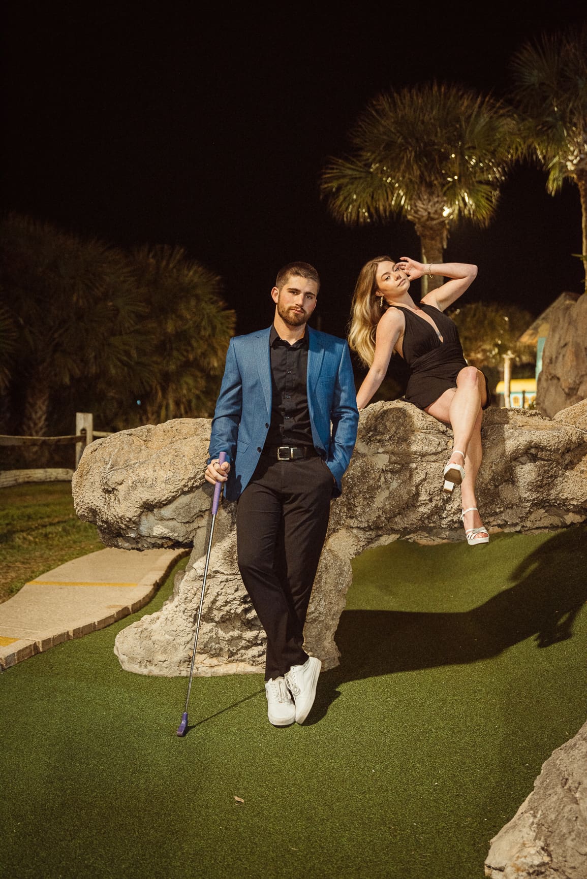 Couple styled in bold editorial outfits for engagement photos at night with dramatic lighting