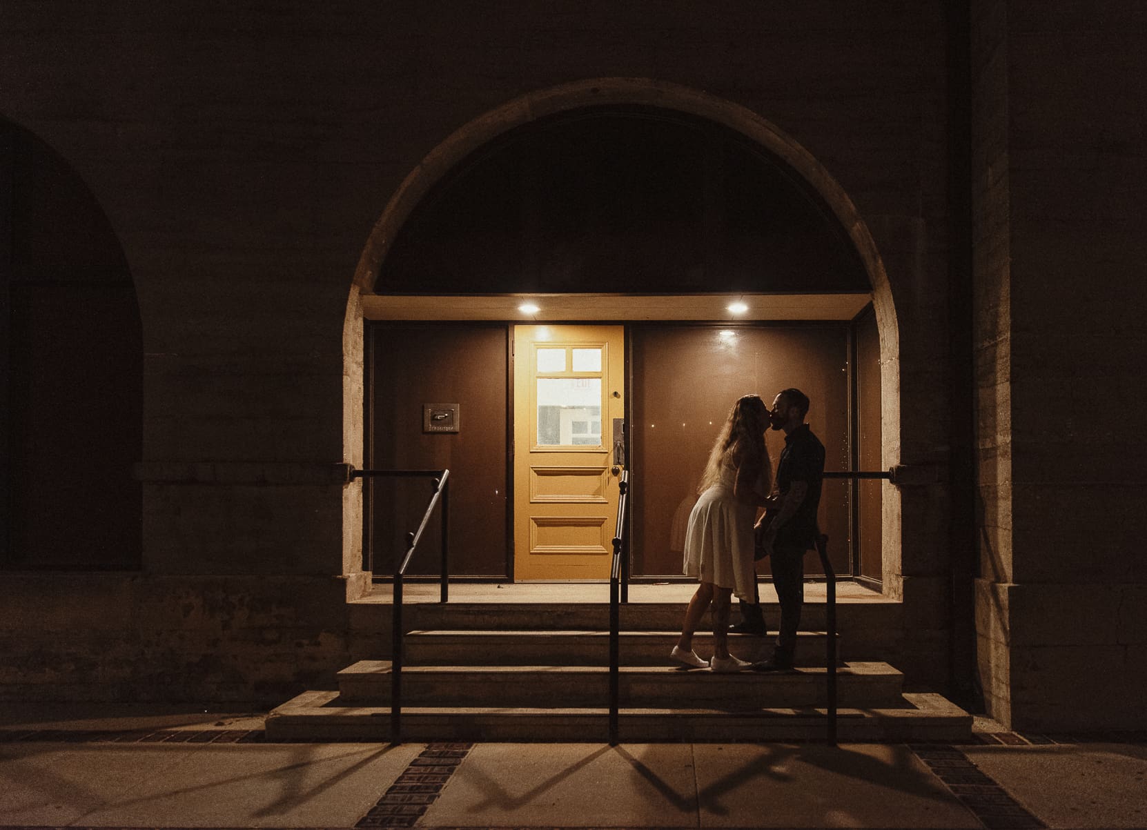 Romantic nighttime elopement portrait in downtown St Augustine with couple kissing under warm light. 