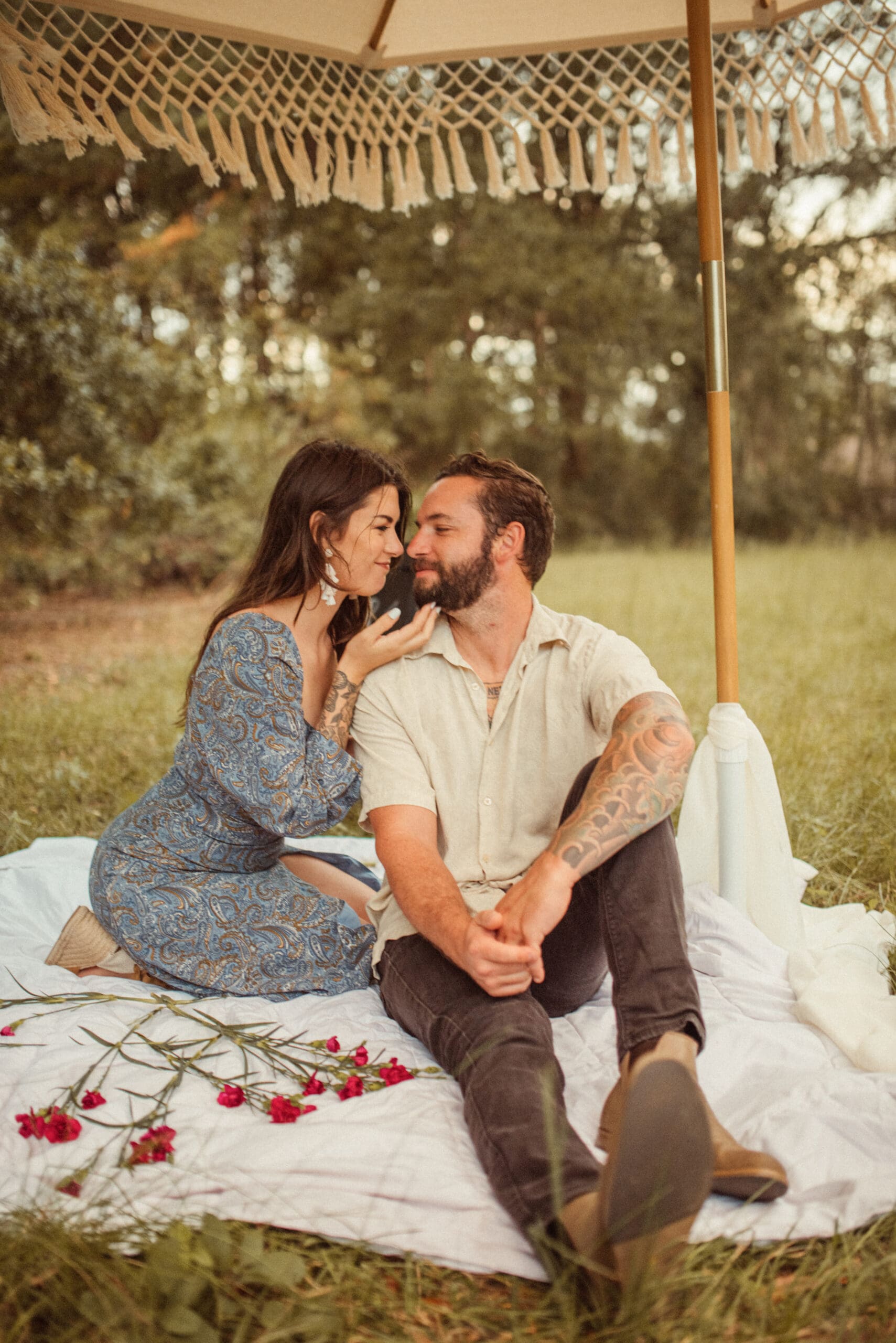 Couple sitting on a picnic blanket in a field sharing an intimate moment during a romantic engagement session in St. Augustine
