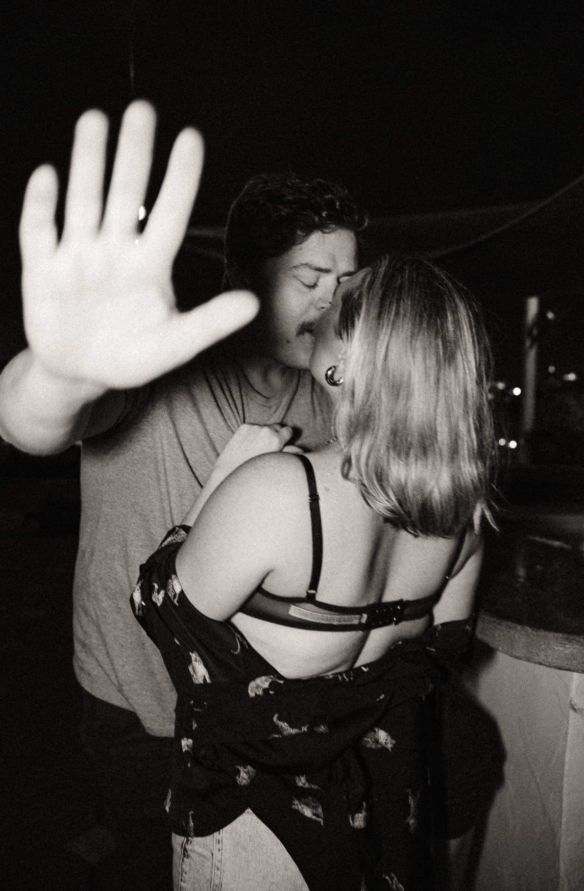 Playful couple kissing with flash photography and motion blur, candid fun engagement photo with spontaneous energy.