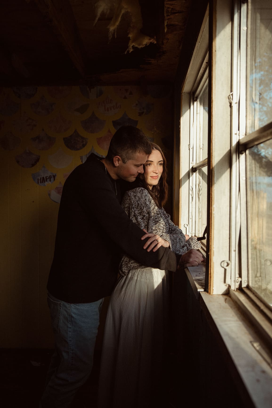 Couple embracing by a window with soft natural light during an intimate