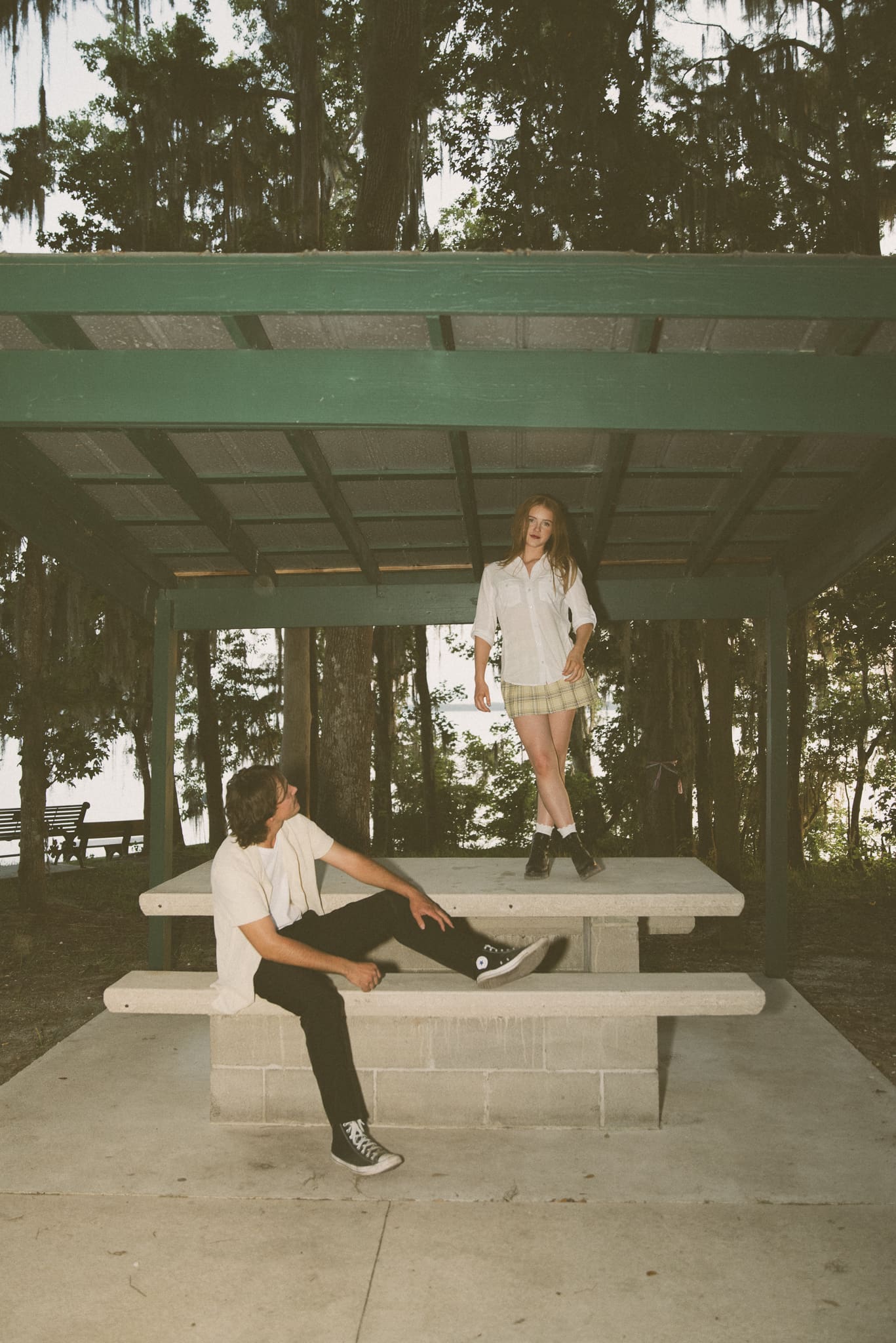Couple wearing overalls in wooded setting for editorial photo session, creative styling with earthy tones and textured outfits. 
