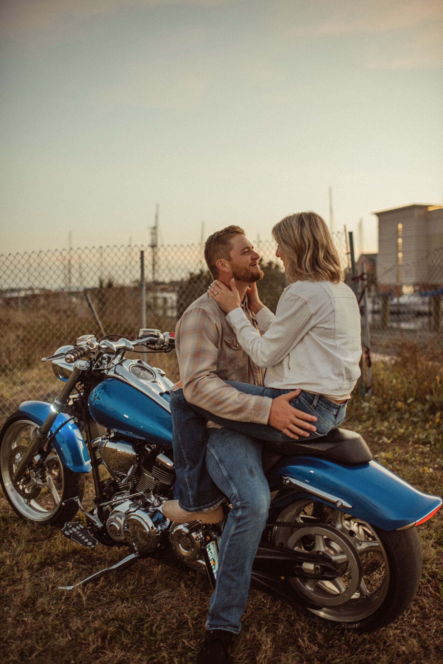 Couple sitting on motorcycle at sunset, fun and playful engagement photos with warm golden light and relaxed connection. 