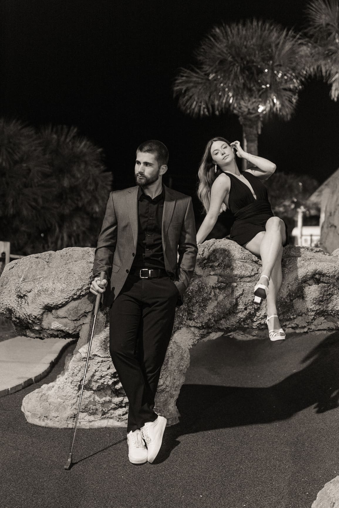 Stylish couple at night with flash photography, woman in black dress and man in suit, editorial night session with dramatic lighting. 