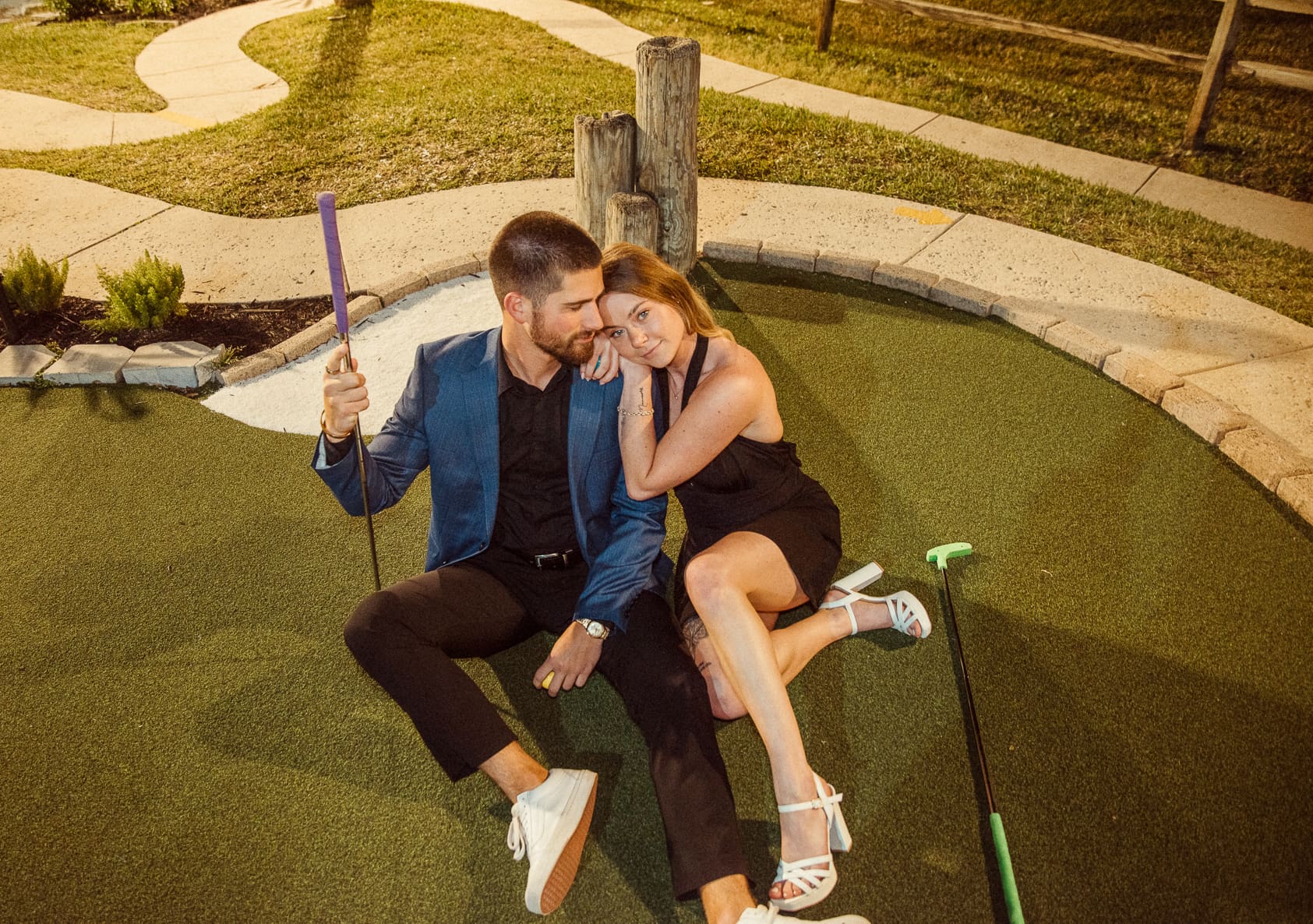Couple dressed in a black dress and blazer sitting close together showing a more elevated romantic engagement outfit style
