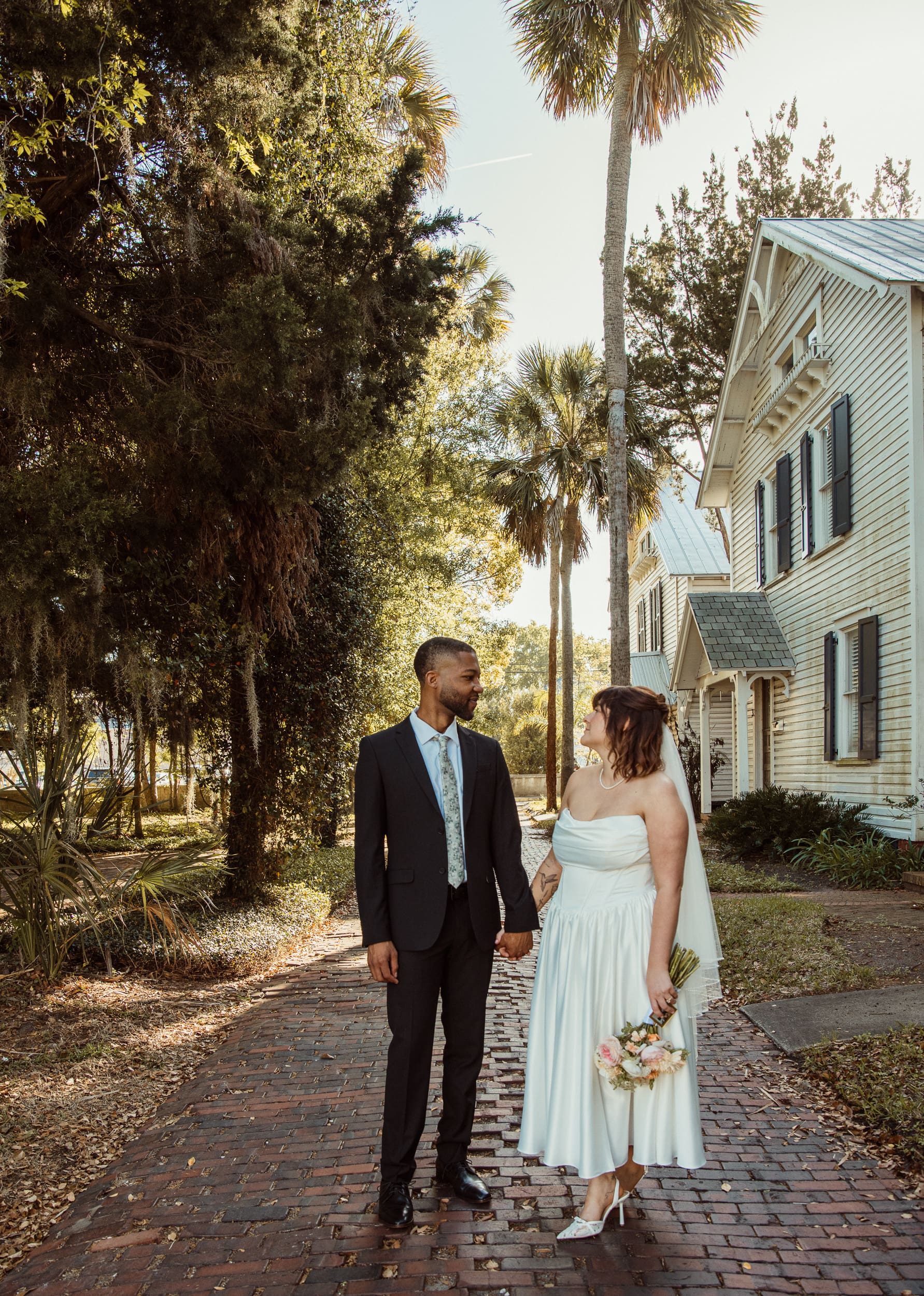 Couple walking along palm-lined path near Lightner Museum in St Augustine after elopement.