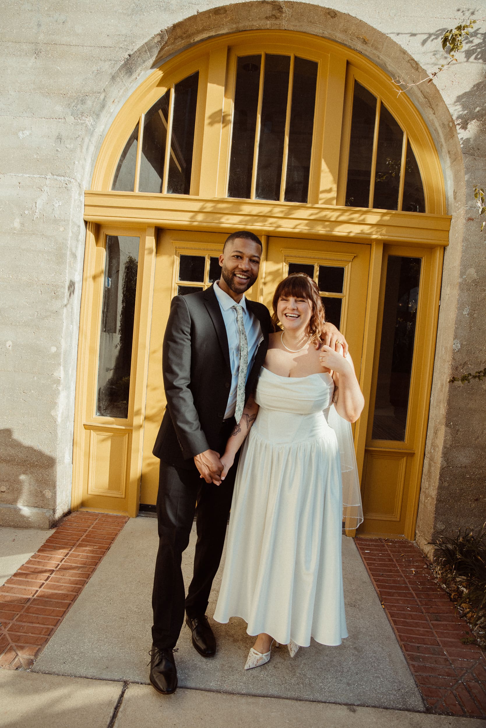 Couple posing in front of a yellow doorway in the Lightner Museum courtyard in downtown St. Augustine after their elopement. 