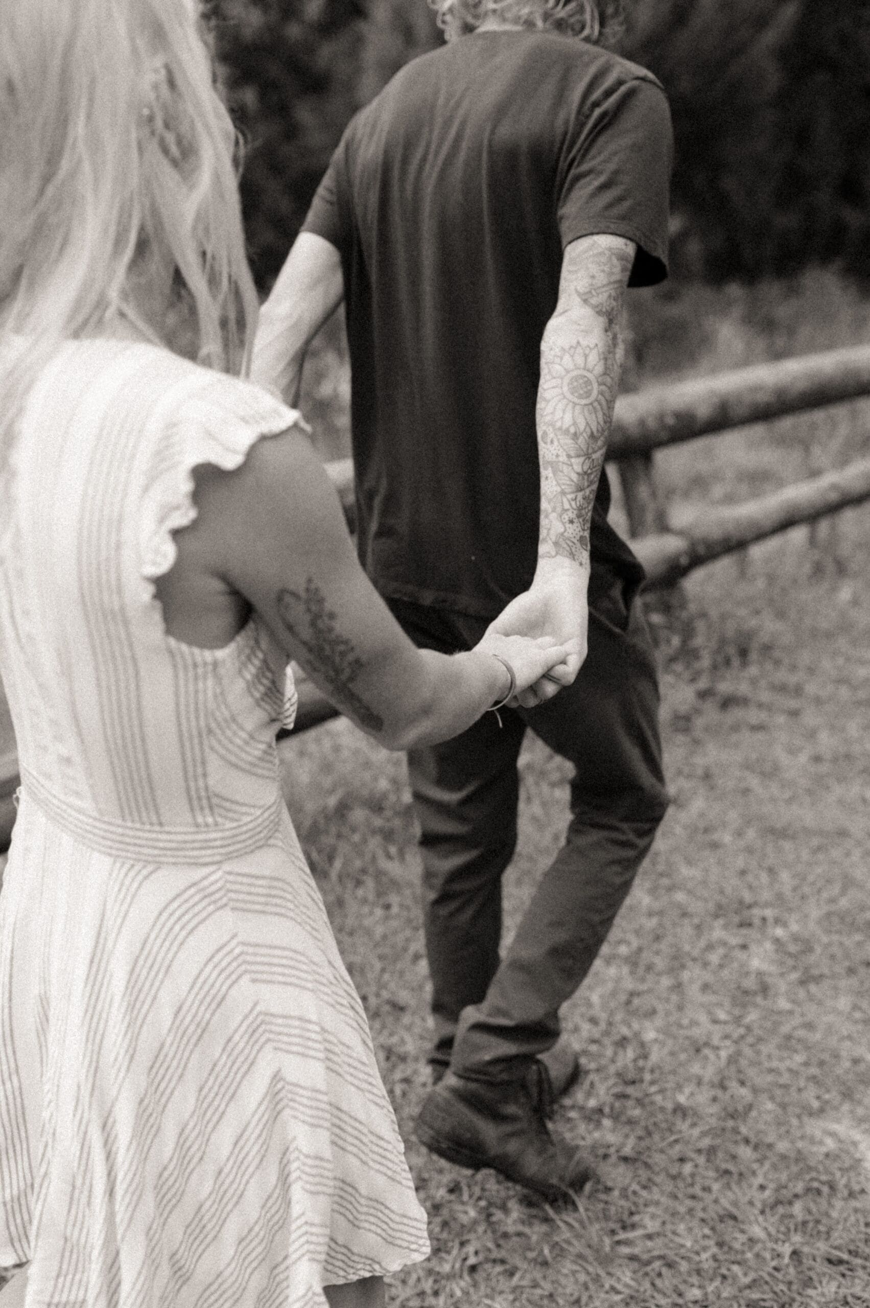 Couple walking away hand in hand with a flowing dress creating soft movement in a romantic engagement session. 