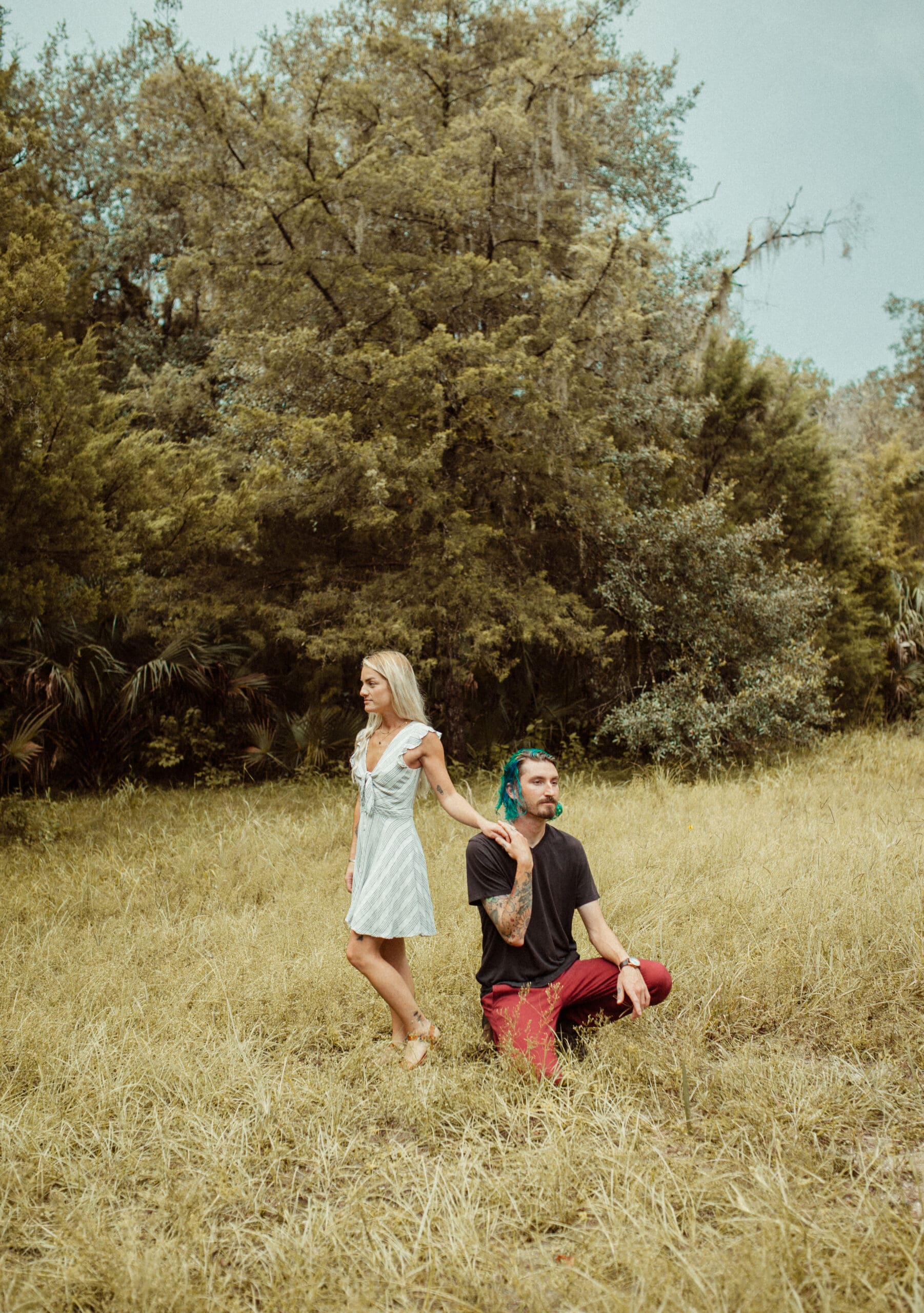 couple in open field with contrasting outfit colors, editorial engagement session with bold styling and relaxed posing. 