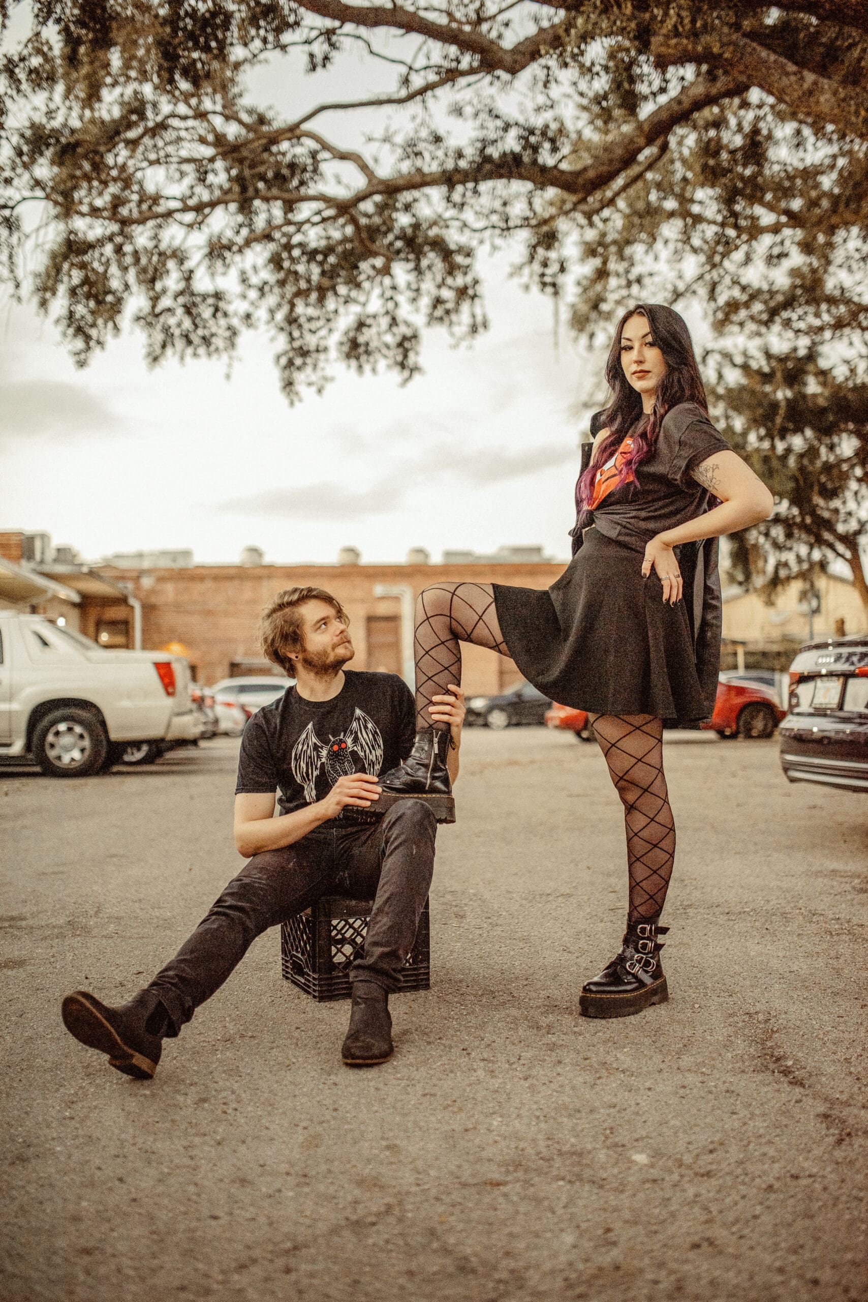 Playful editorial couple posing in urban setting with bold outfits and confident styling, creative engagement photo idea. 