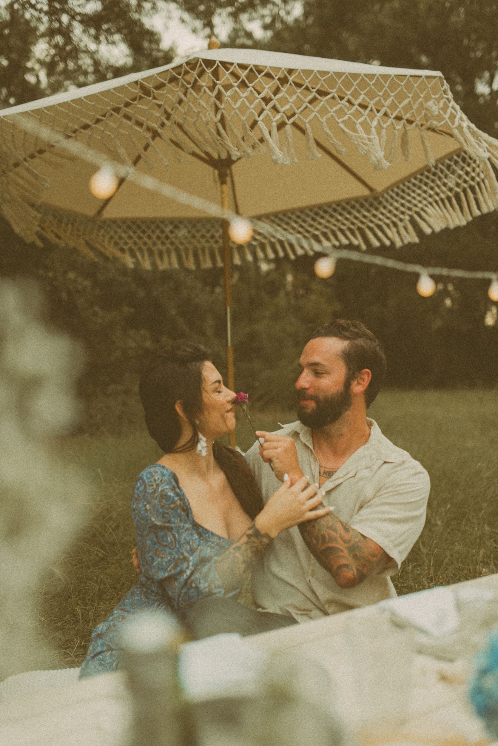 Couple laughing together under a fringed umbrella during a romantic backyard engagement session in Mandarin, Florida.