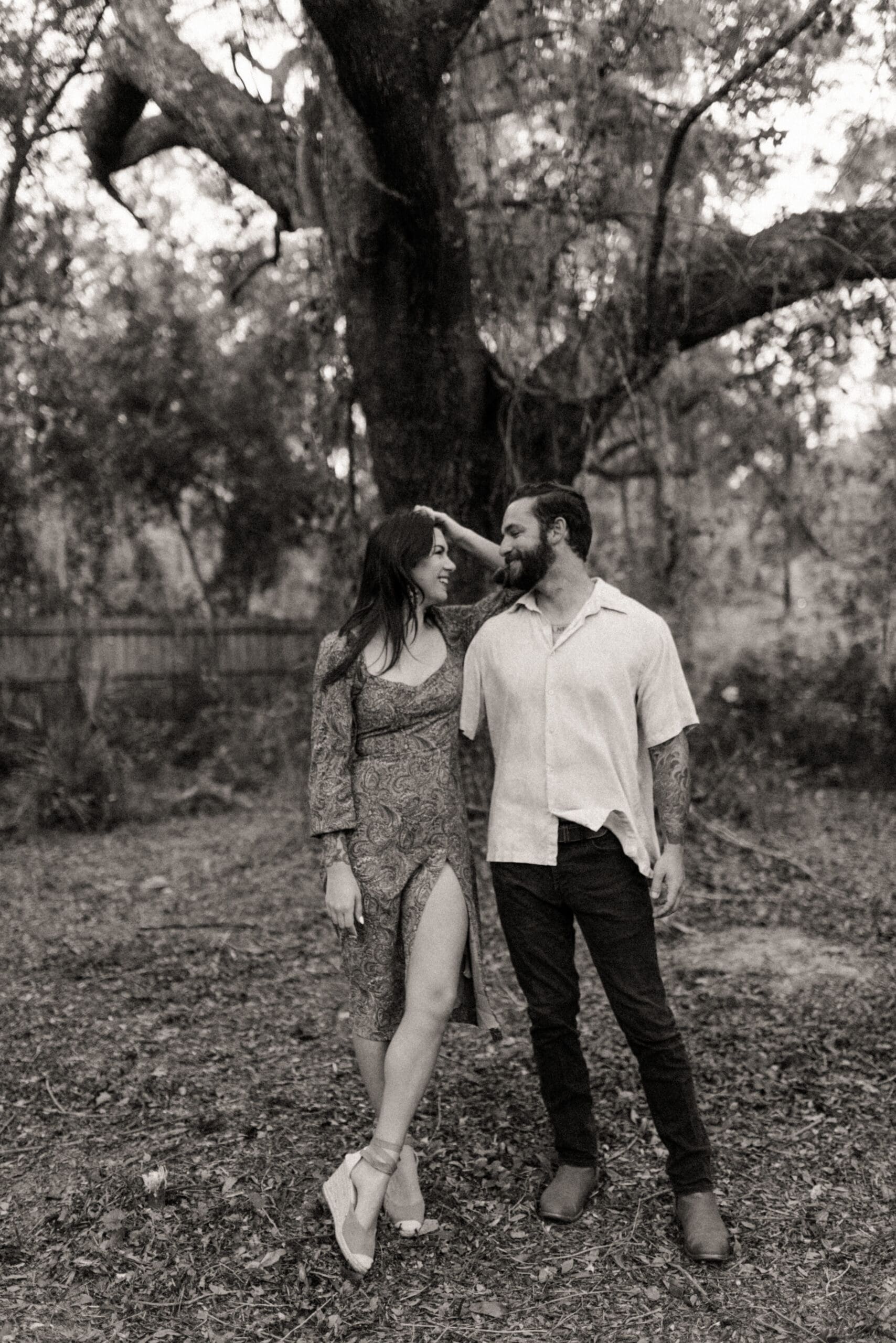Black and white engagement photo of a couple in front of a large live oak tree during a St. Augustine engagement session. 