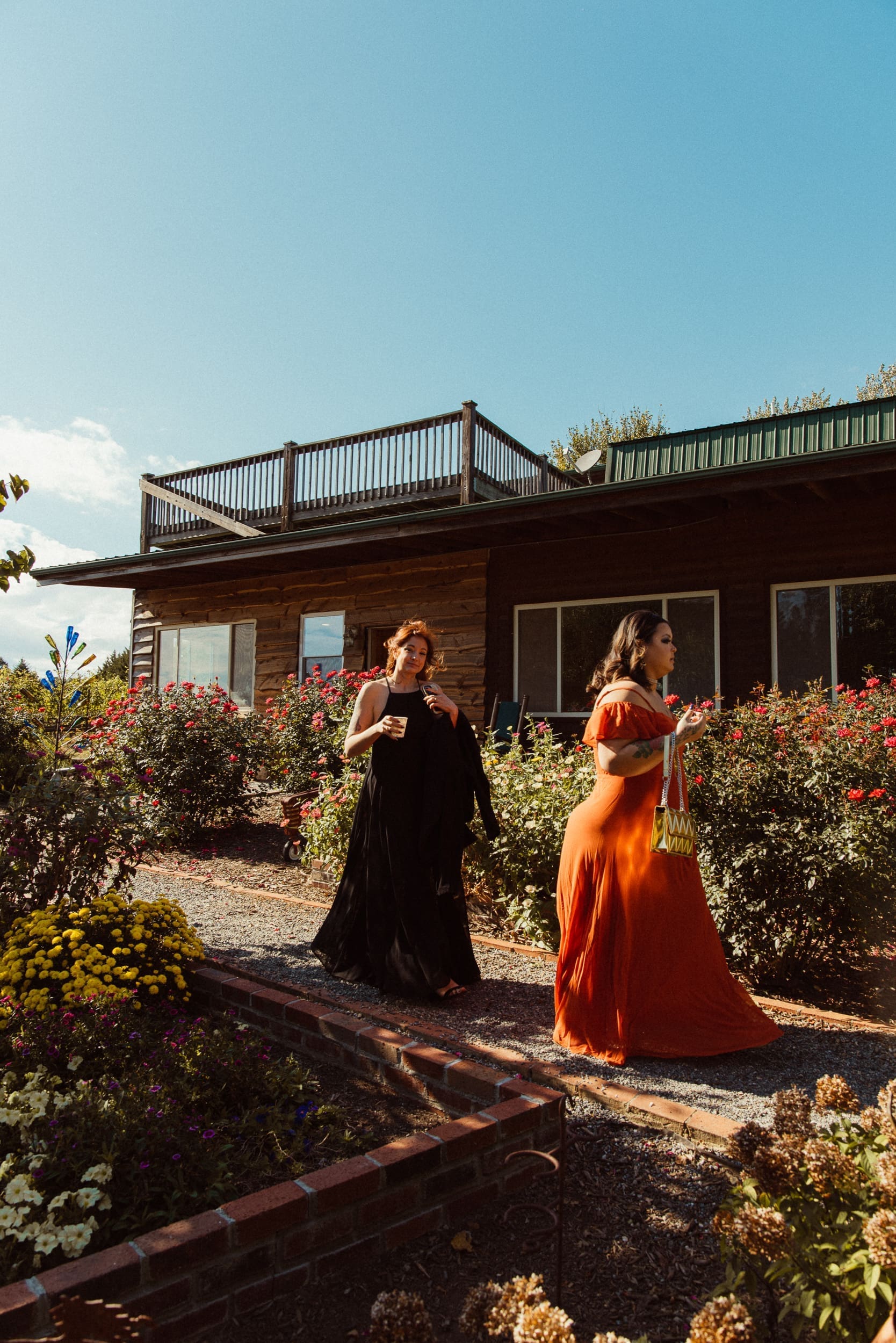 Wedding guests in colorful gowns walking through rose garden at Parker-Binns Vineyard North Carolina. 