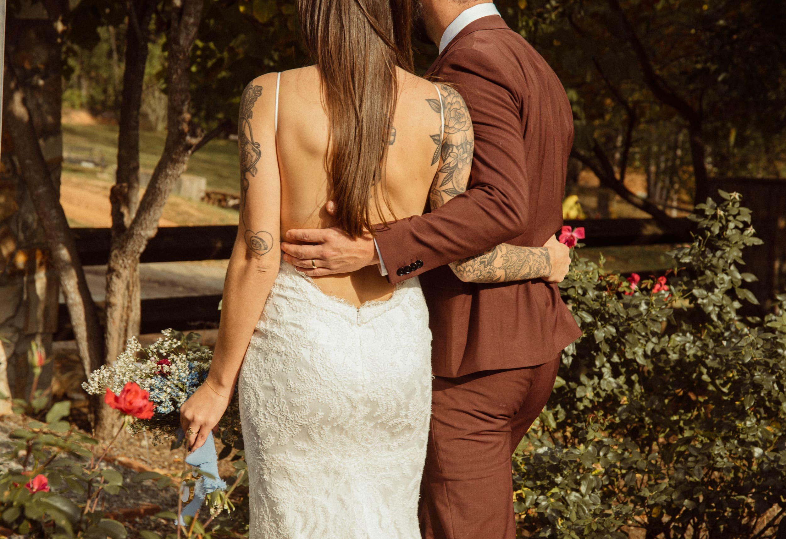 Intimate detail of groom's arm wrapped around bride in romantic garden setting in North Carolina vineyard. 