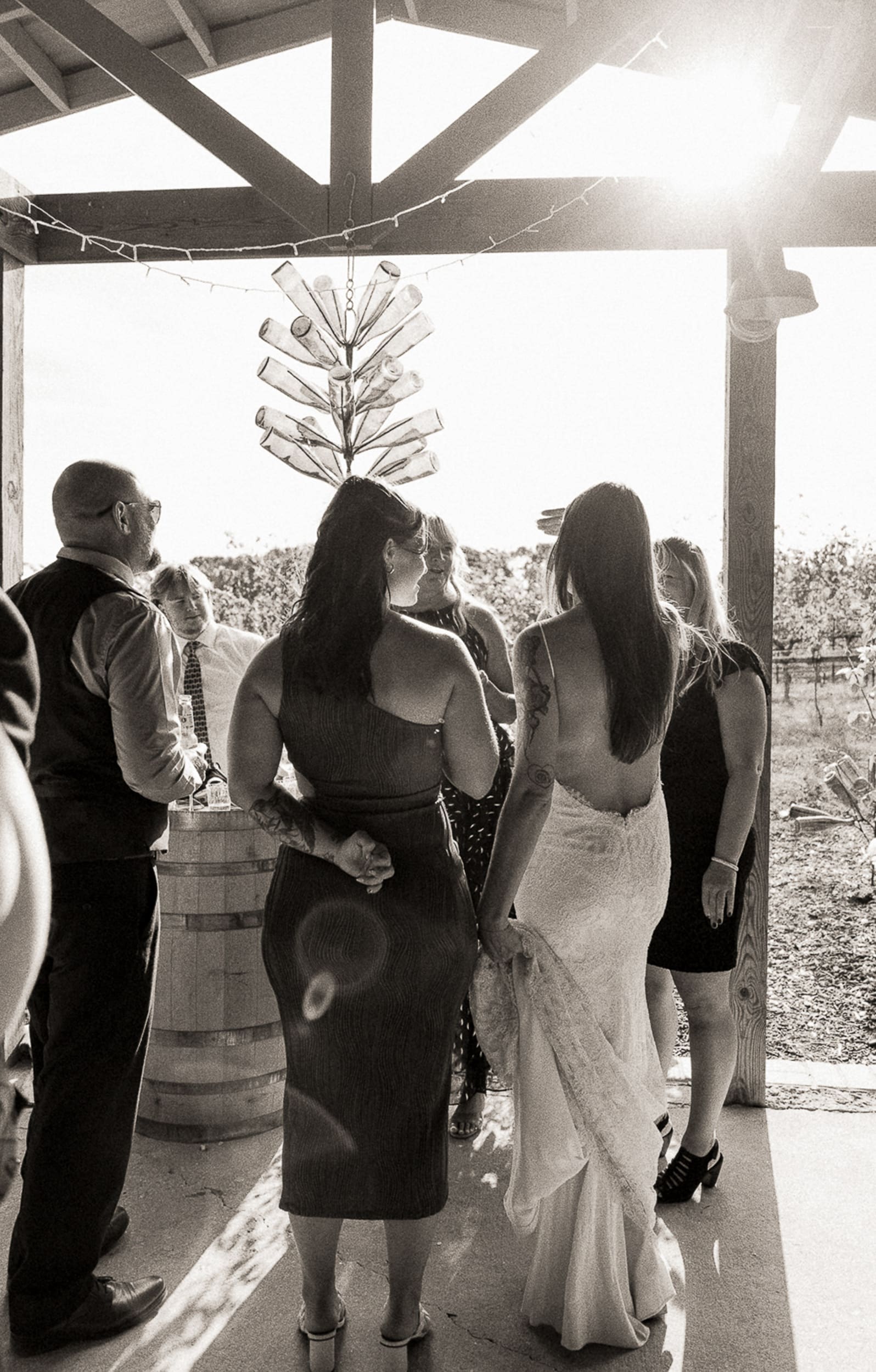 Black and white candid of bride and guests gathered under vineyard pavilion at Parker-Binns North Carolina. 