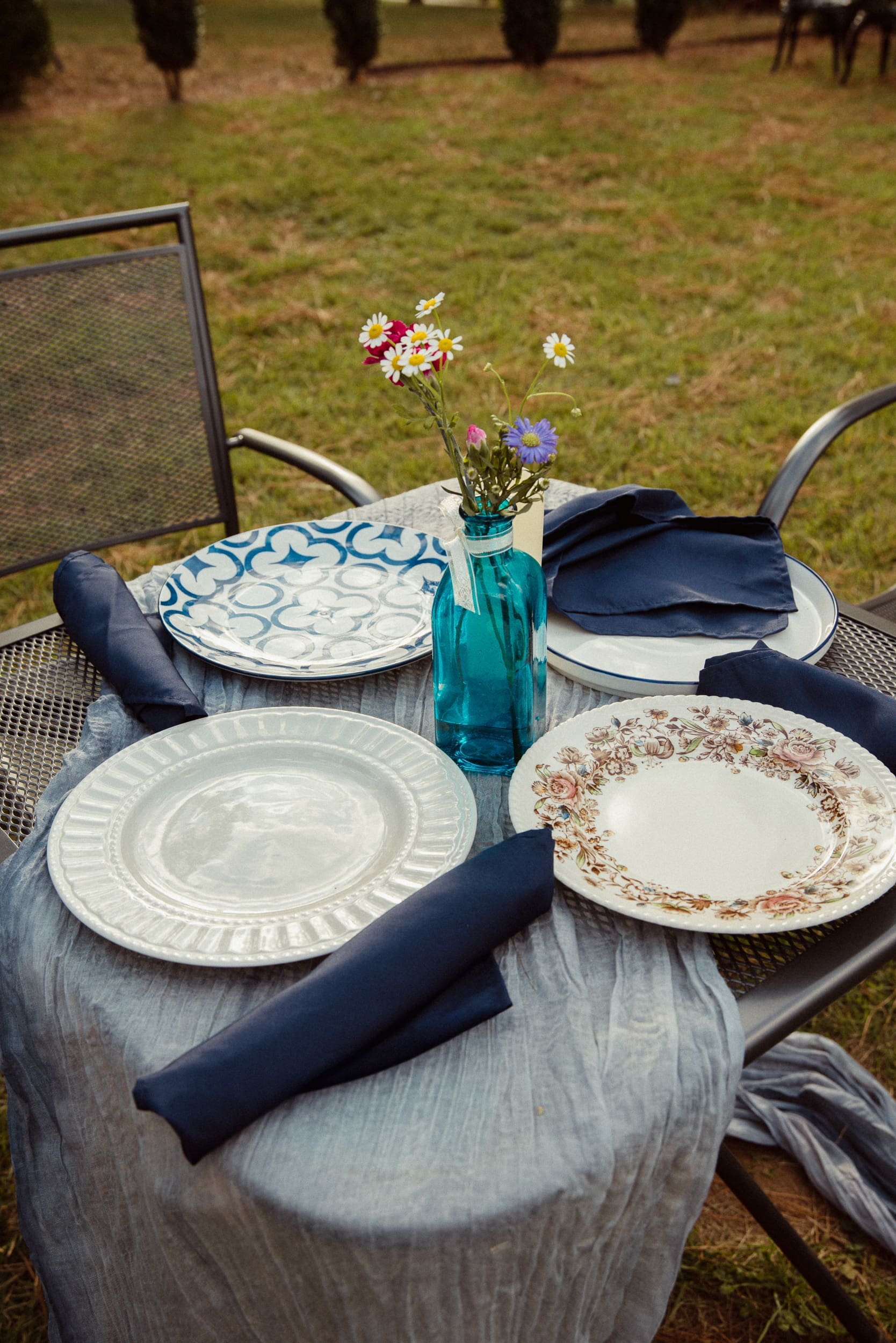 Outdoor wedding reception table detail with mismatched vintage plates and wildflowers at Parker-Binns Vineyard North Carolina, Brandi Denslow Photography. 