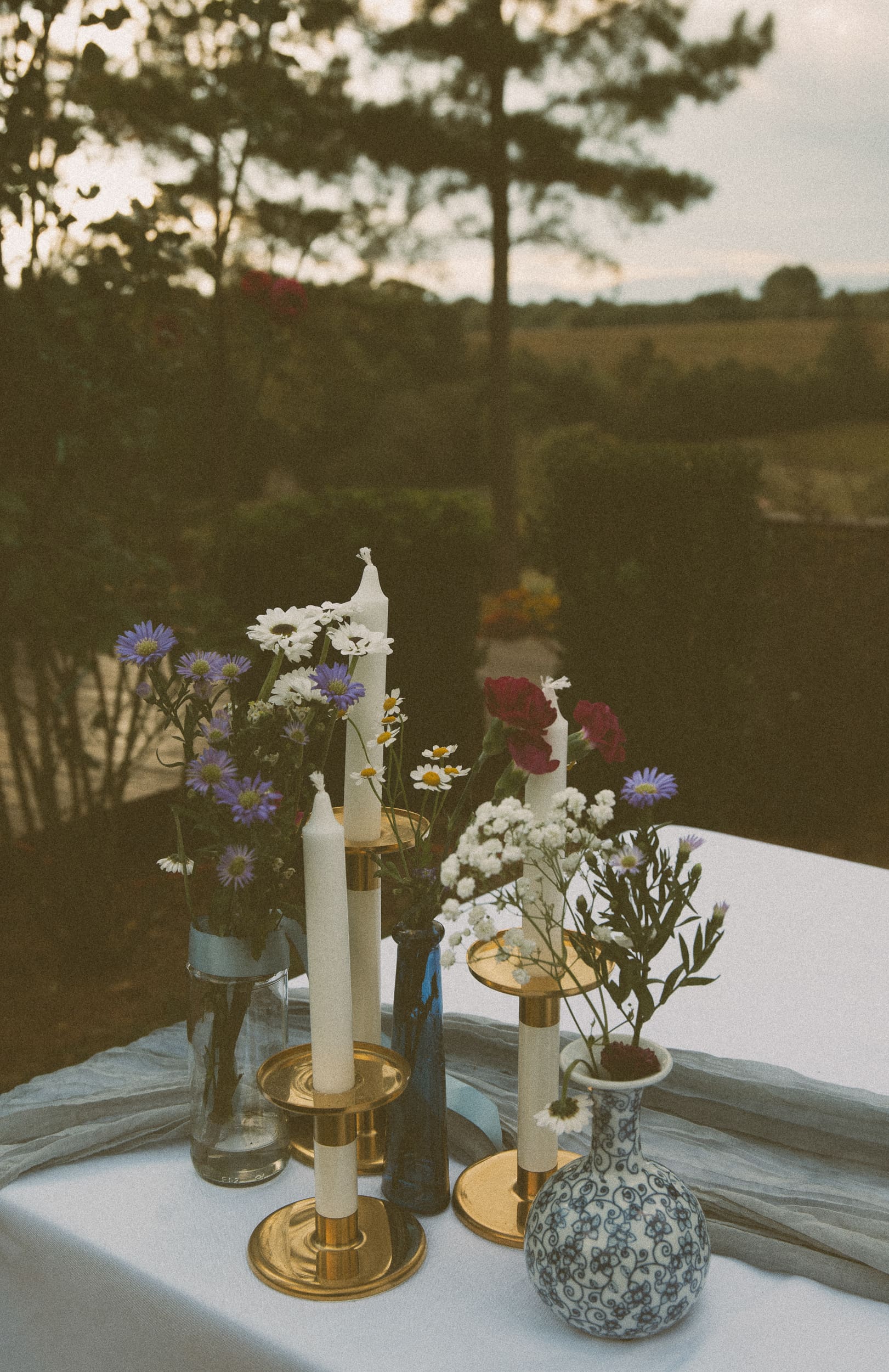 Wedding reception table detail of vintage vases for wildflowers and brass candlesticks during outdoor reception at Parker-Binns Vineyard. 