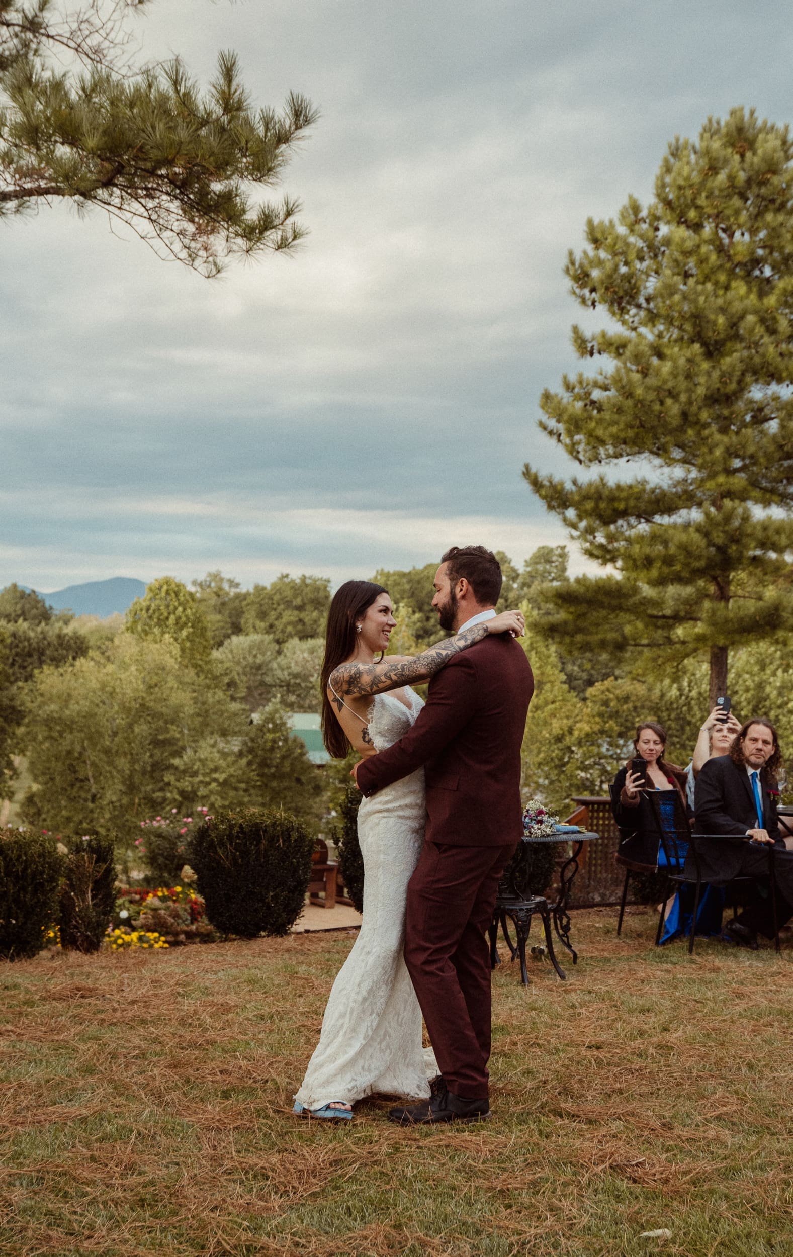 Bride and groom dance closely during their first dance on top of a hill overlooking the vineyard and mountains below during an autumn wedding at Parker-Binns Vineyard, North Carolina. 