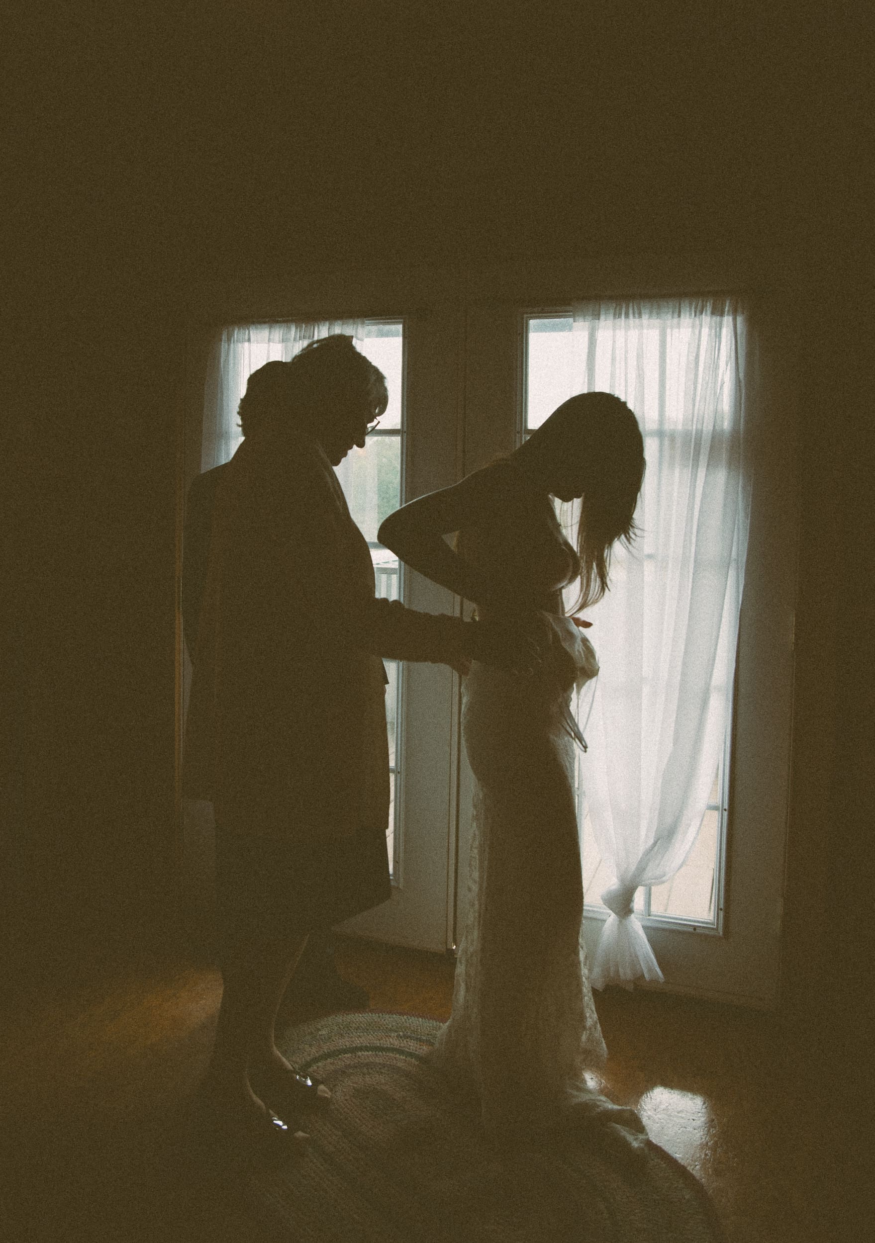 Silhouette of grandmother helping bride into wedding dress at chateau window, Parker-Binns Vineyard North Carolina, Brandi Denslow Photography.