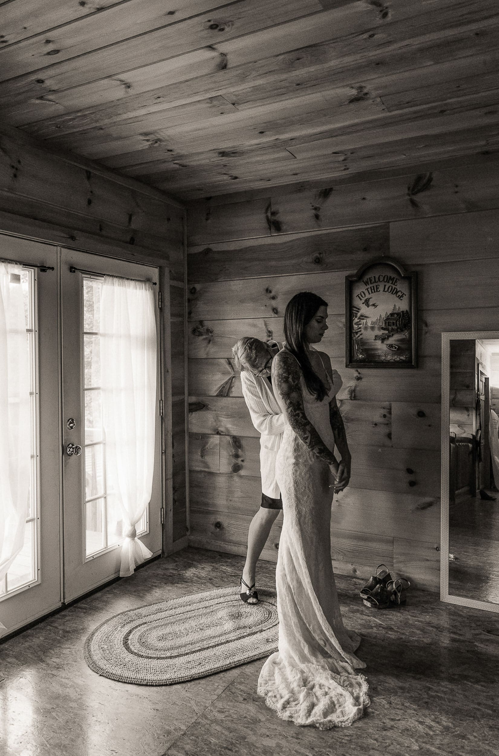 Black and white photo of bride being laced into wedding dress inside rustic chateau at Parker-Binns Vineyard North Carolina. 