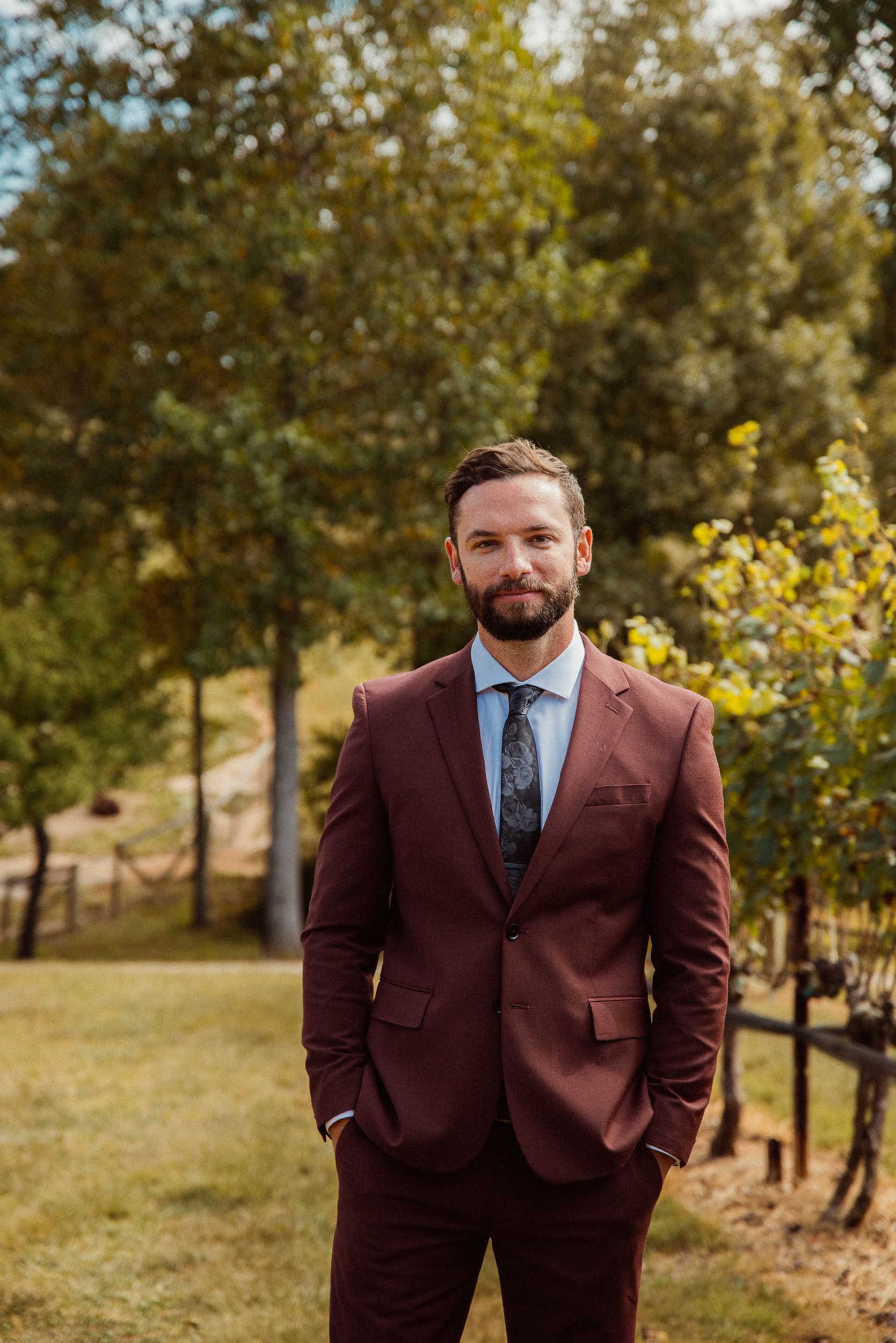 Groom portrait in burgundy suit with autumn vineyard trees at Parker-Binns Vineyard.
