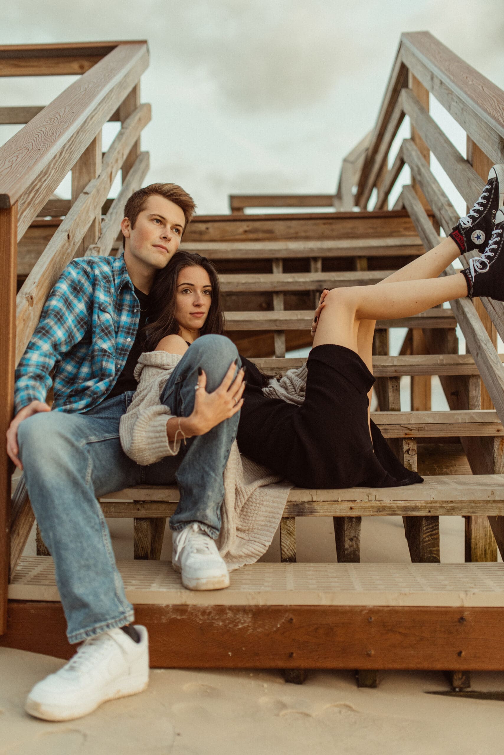 Couple posed casually on a wooden beach stairs during a relaxed Florida engagement session. 