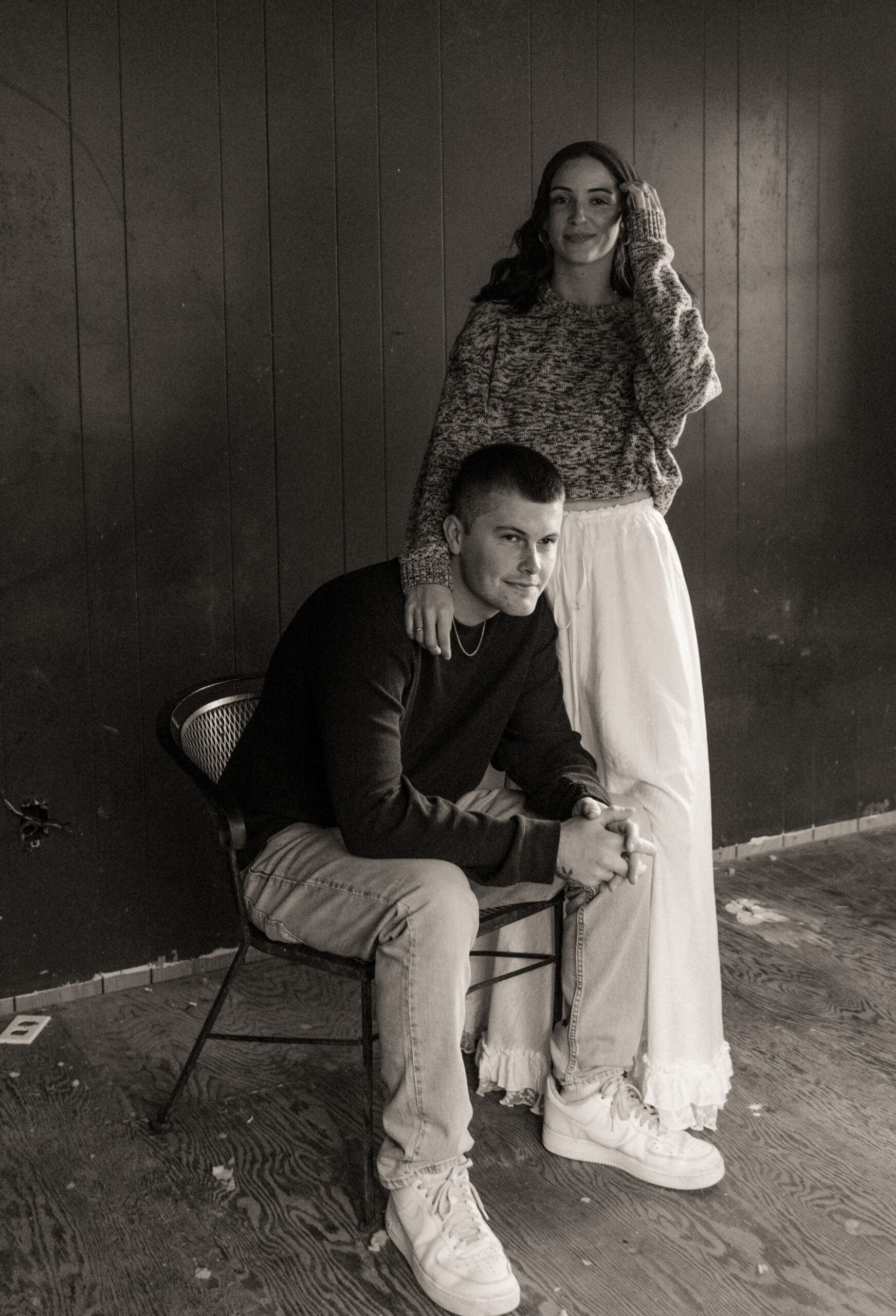 Black and white editorial engagement portrait of a couple against a dark wood backdrop in St. Augustine, Florida. 
