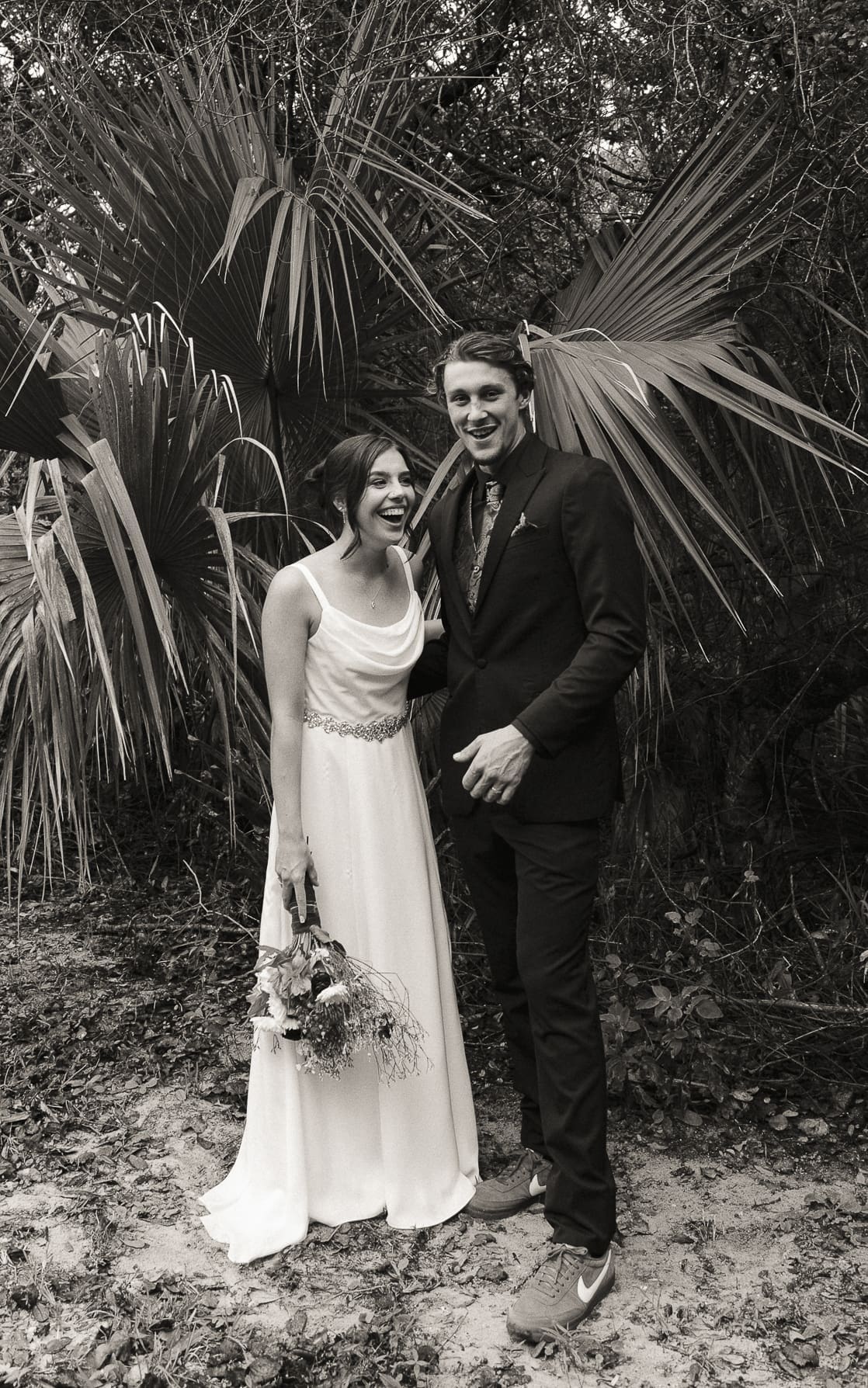 Film-style black and white wedding portrait of bride and groom in tropical Florida setting, Brandi Denslow Photography.