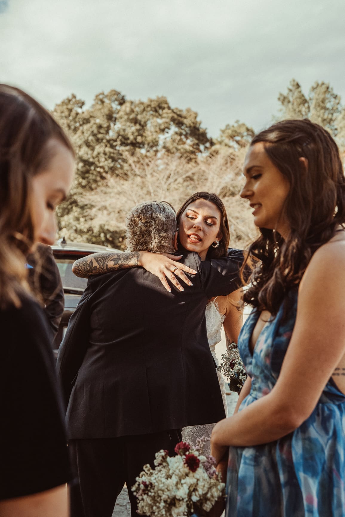 Emotional bride embracing a wedding guest surrounded by bridesmaids, candid documentary wedding photography by Brandi Denslow. 