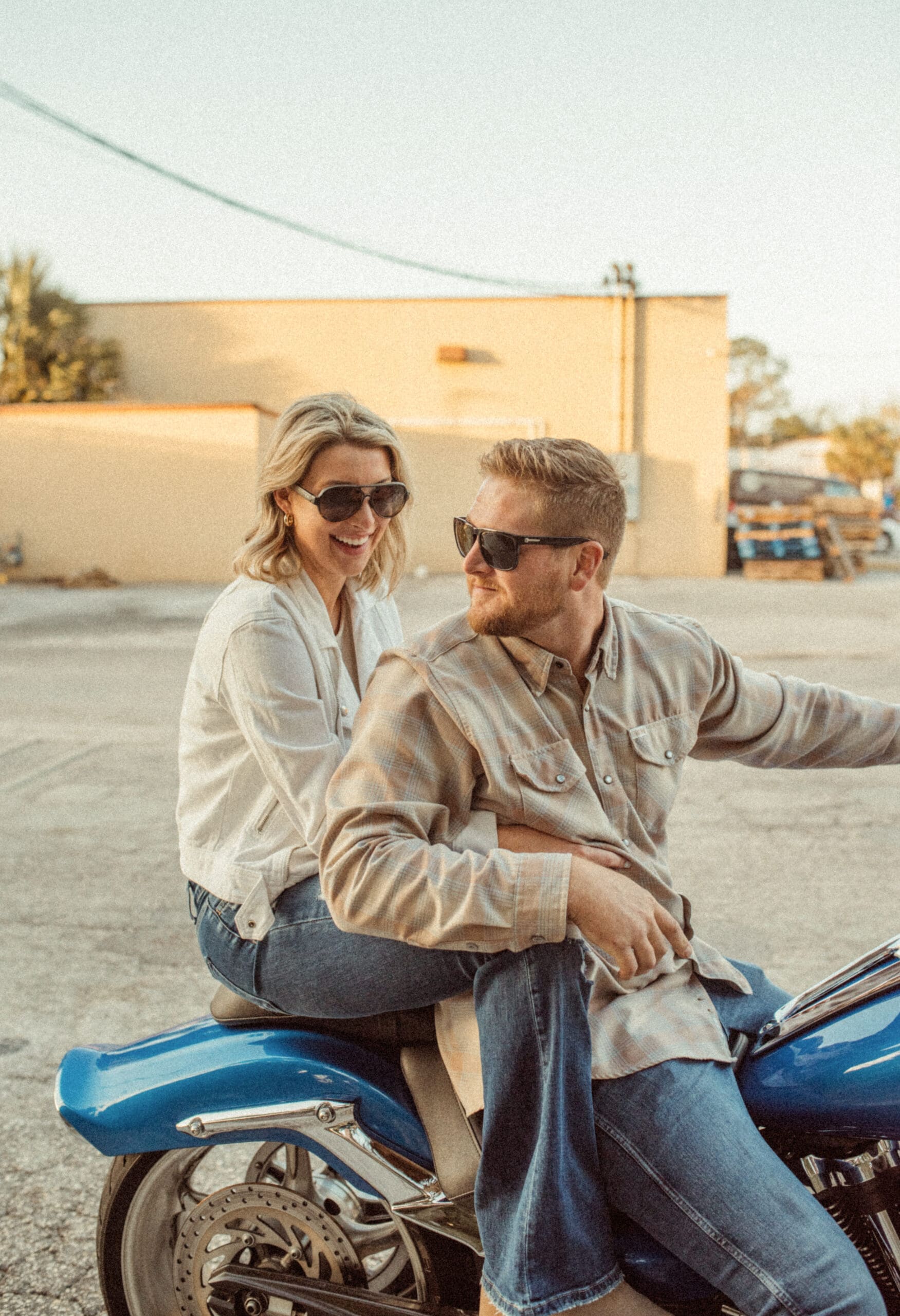 Couple laughing together on a motorcycle during a golden hour engagement session photographed by a St. Augustine wedding photographer. 