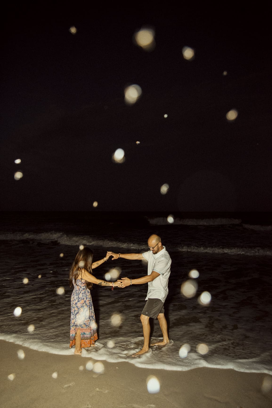 Couple dancing at the ocean's edge during a magical night beach engagement session in St. Augustine, Florida. 
