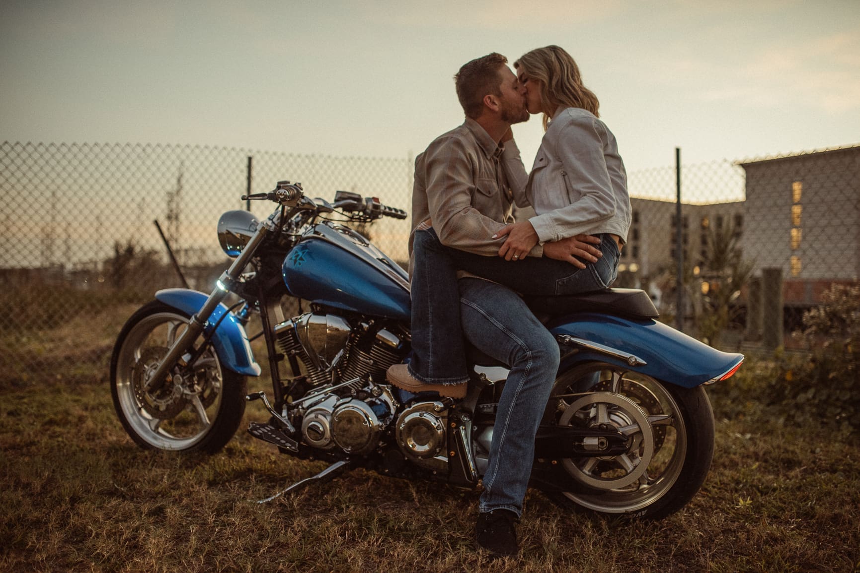 Couple sharing a kiss on a motorcycle during a downtown St. Augustine engagement session photographed at dusk.
