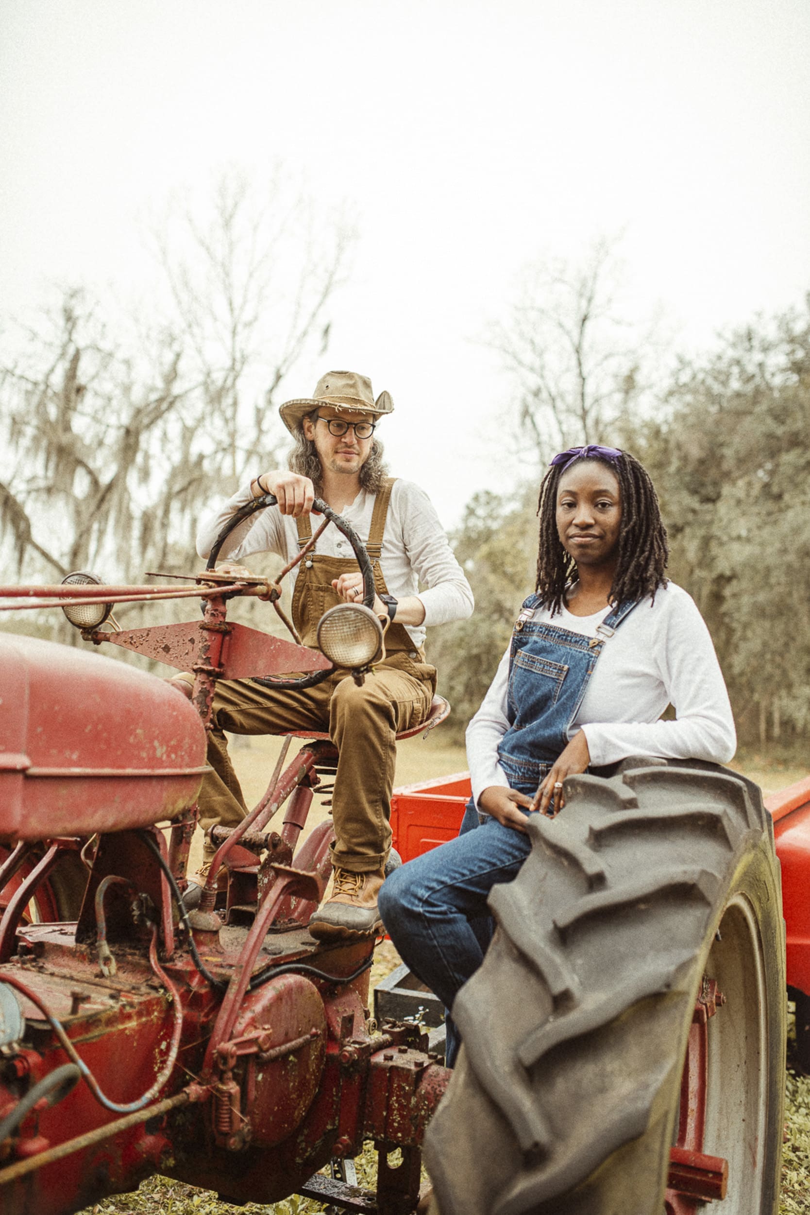 Engaged couple posed on a vintage tractor during a unique farm engagement session in Florida.