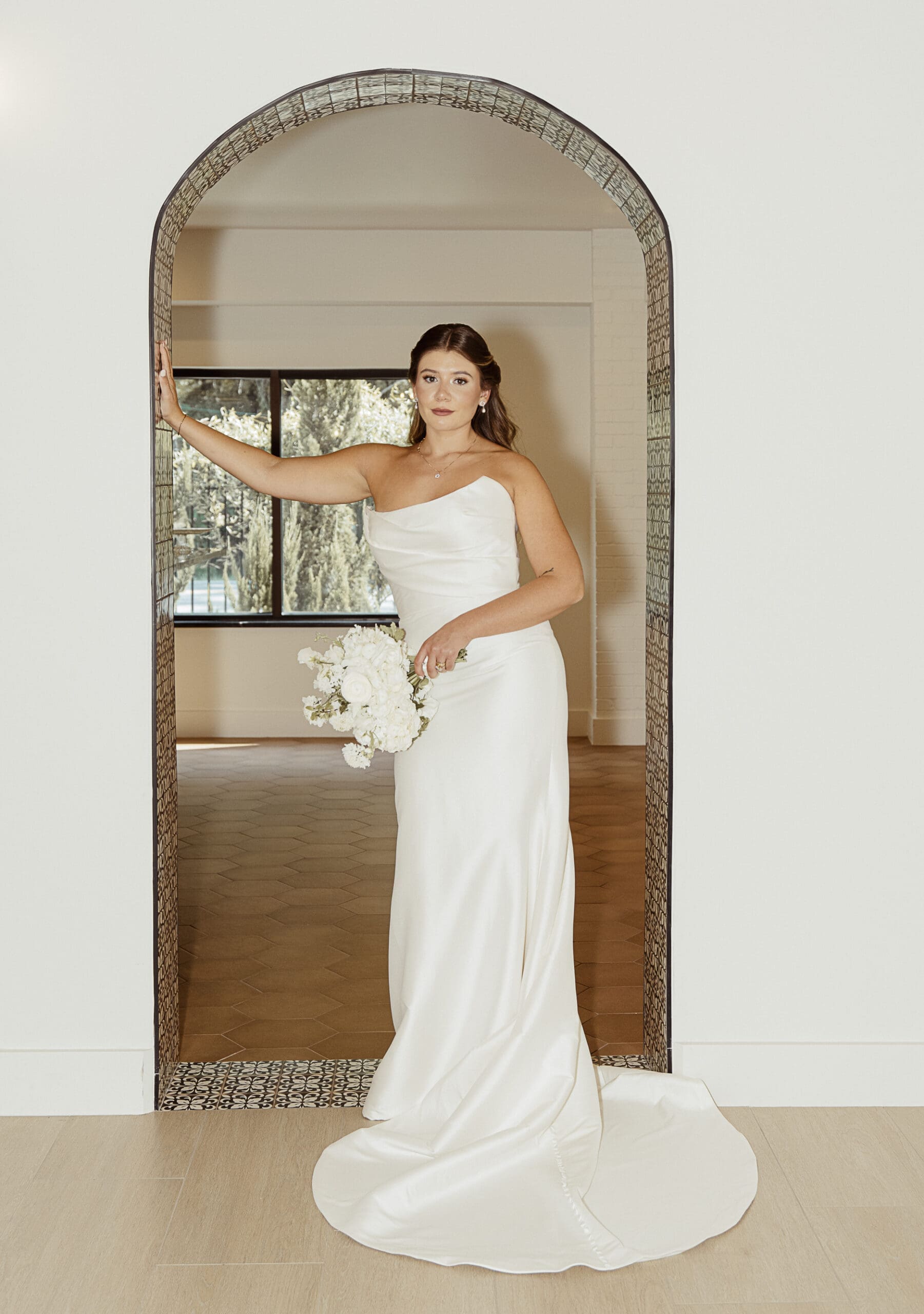 Bride standing in front of vintage archway during wedding day portraits. 