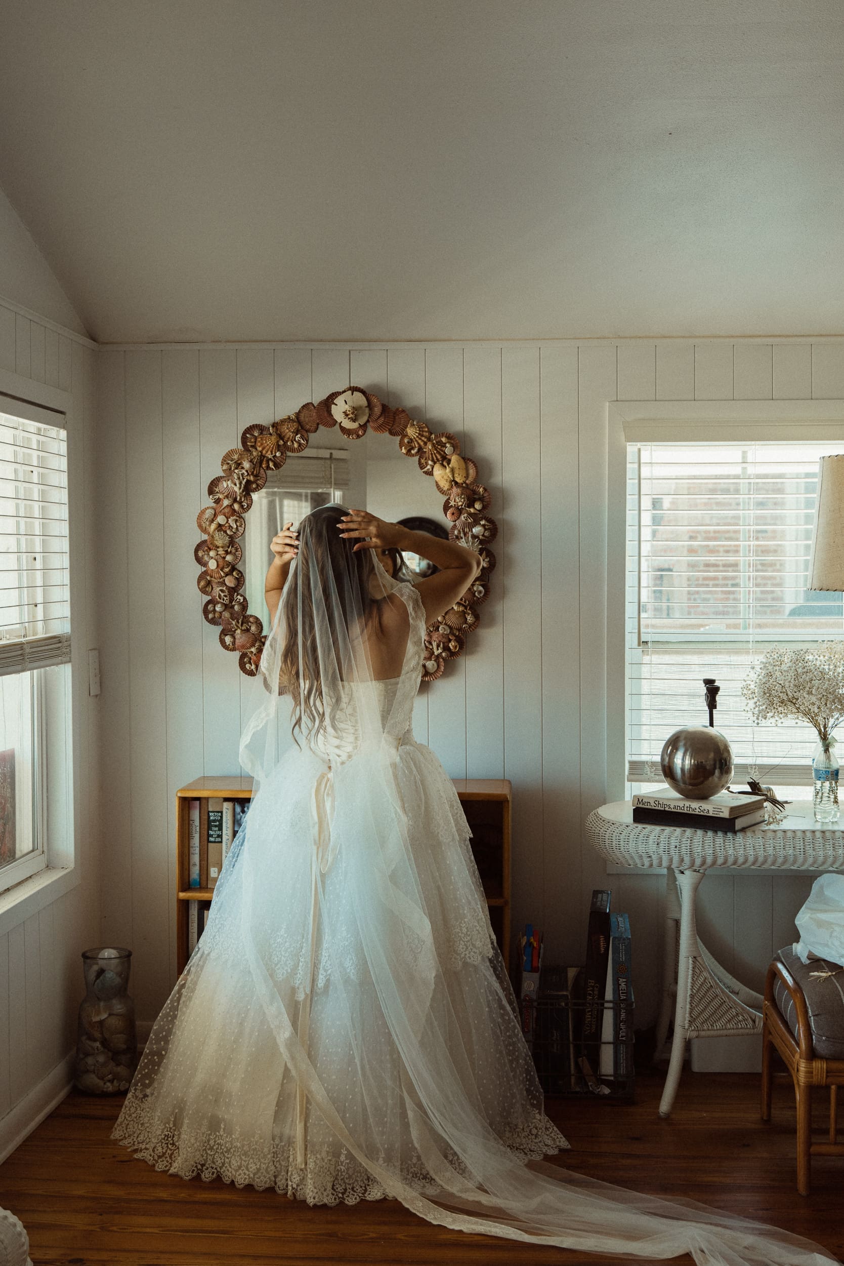 Bride adjusts her veil in a mirror during wedding preparations before the ceremony.