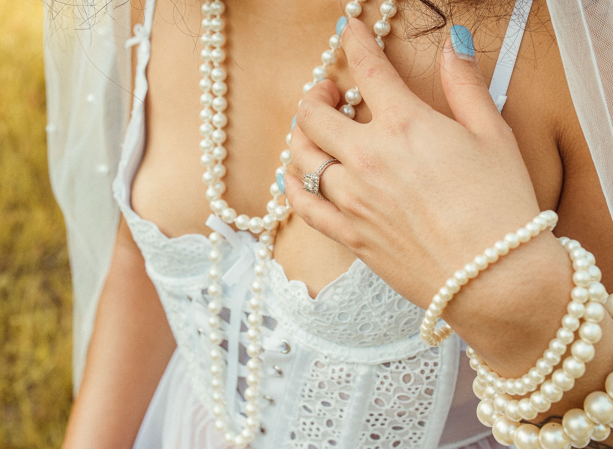 Woman in white bridal lingerie during outdoor embodiment session, highlighting necklace details in natural lighting. 