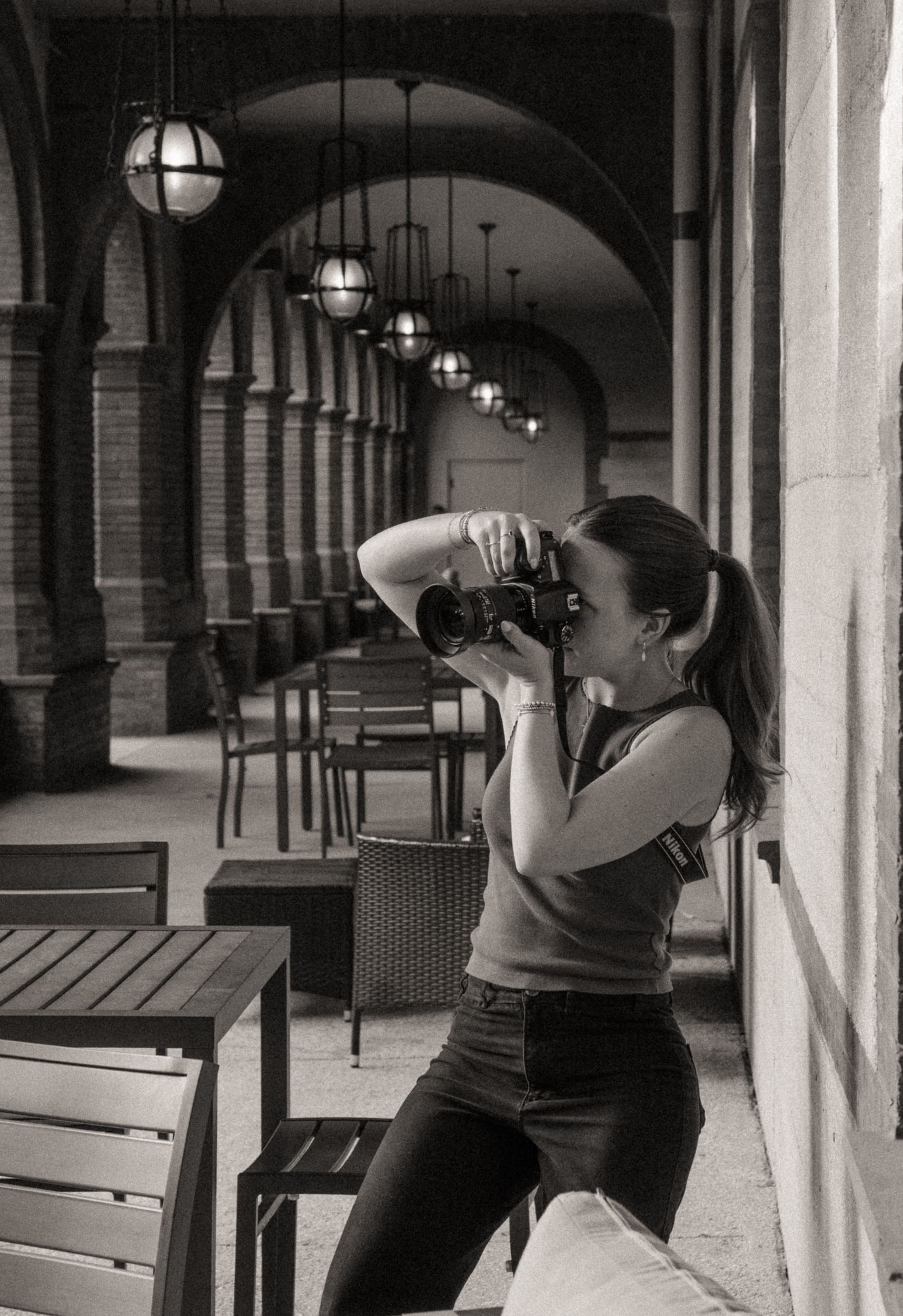 Black and white behind-the-scenes shot of a photographer shooting under Flagler College's arched walkway