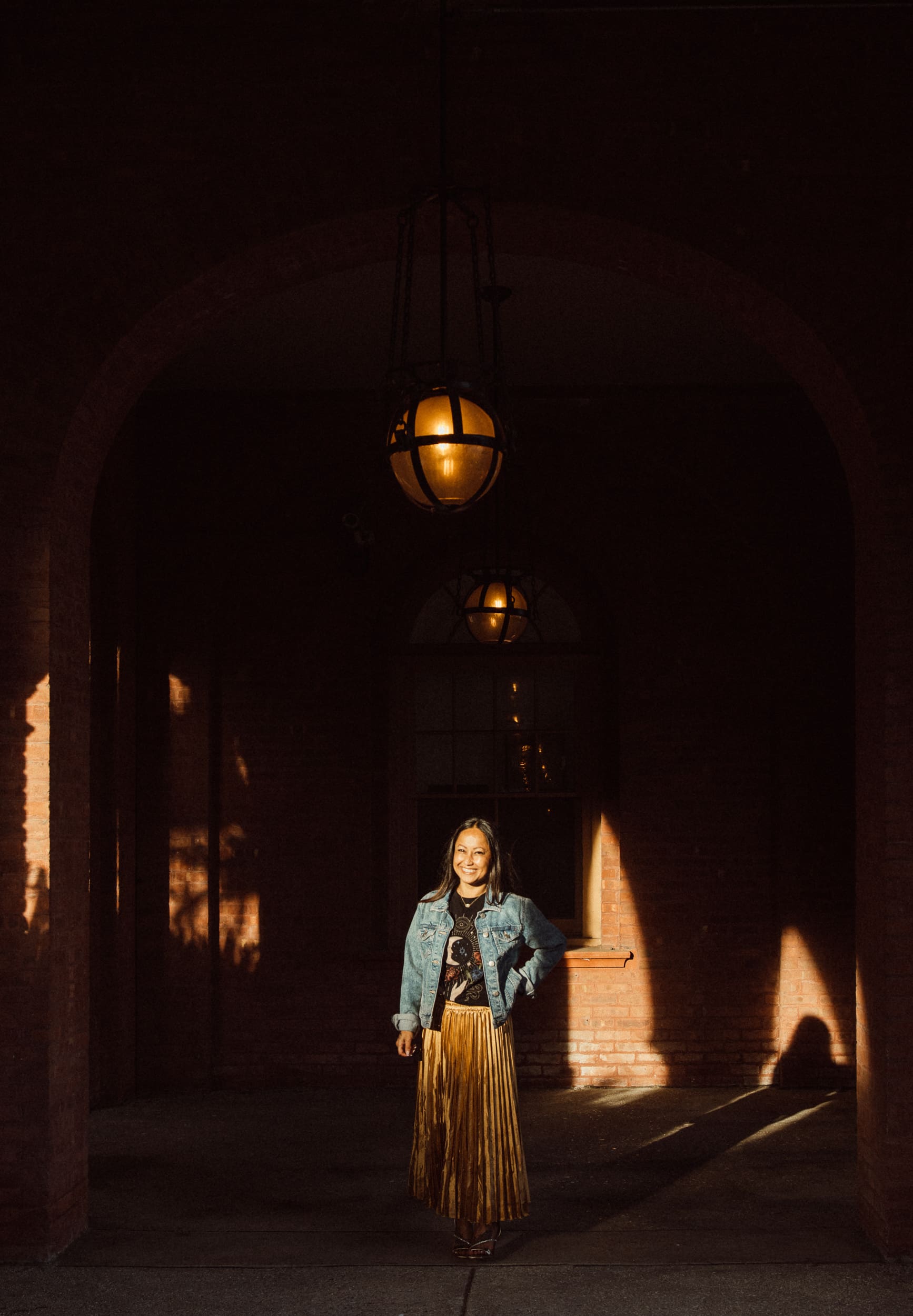Woman posing beneath a warm hanging lantern in a historic St. Augustine archway