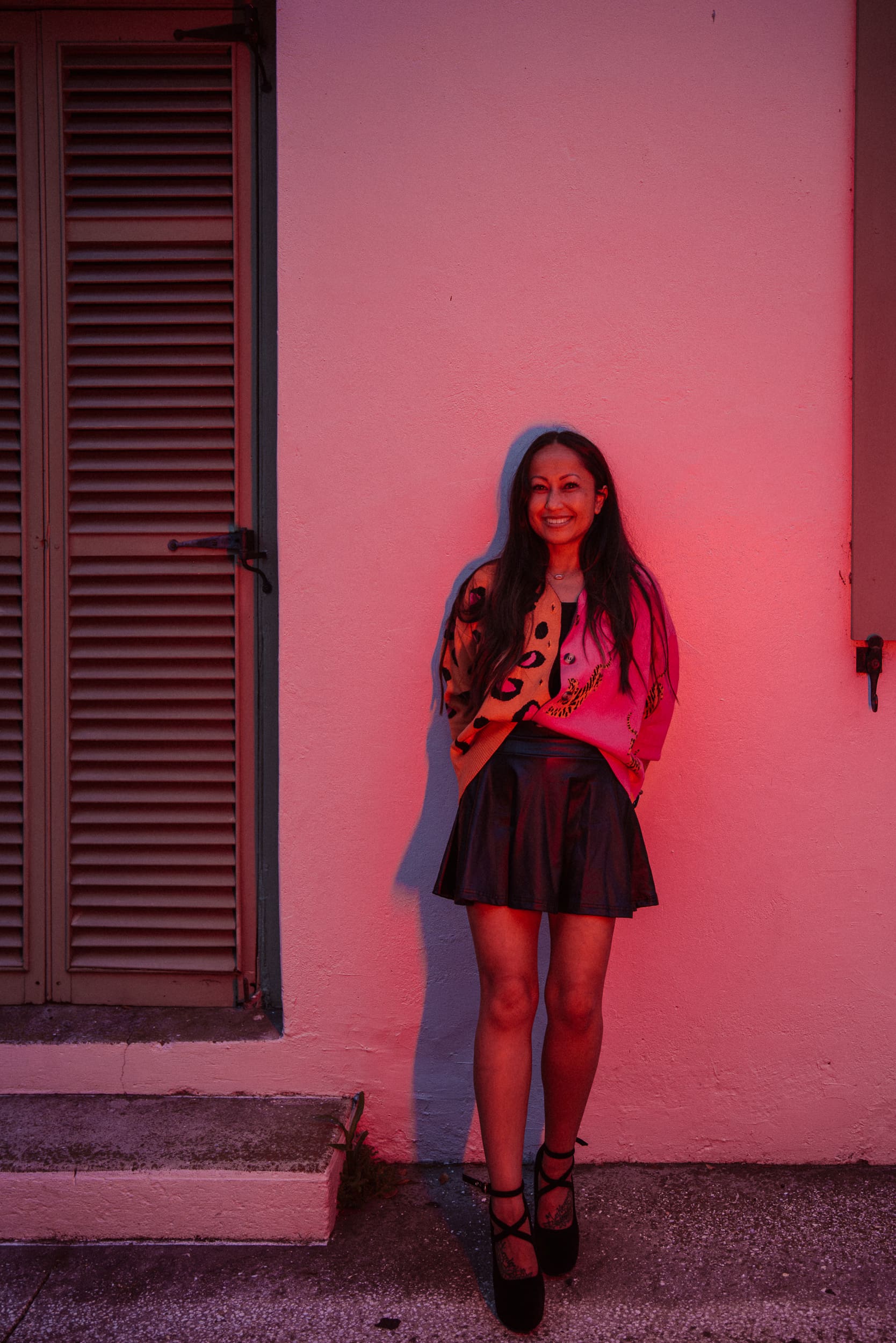 Woman smiling against a pink-lit wall during a St. Augustine night photography workshop