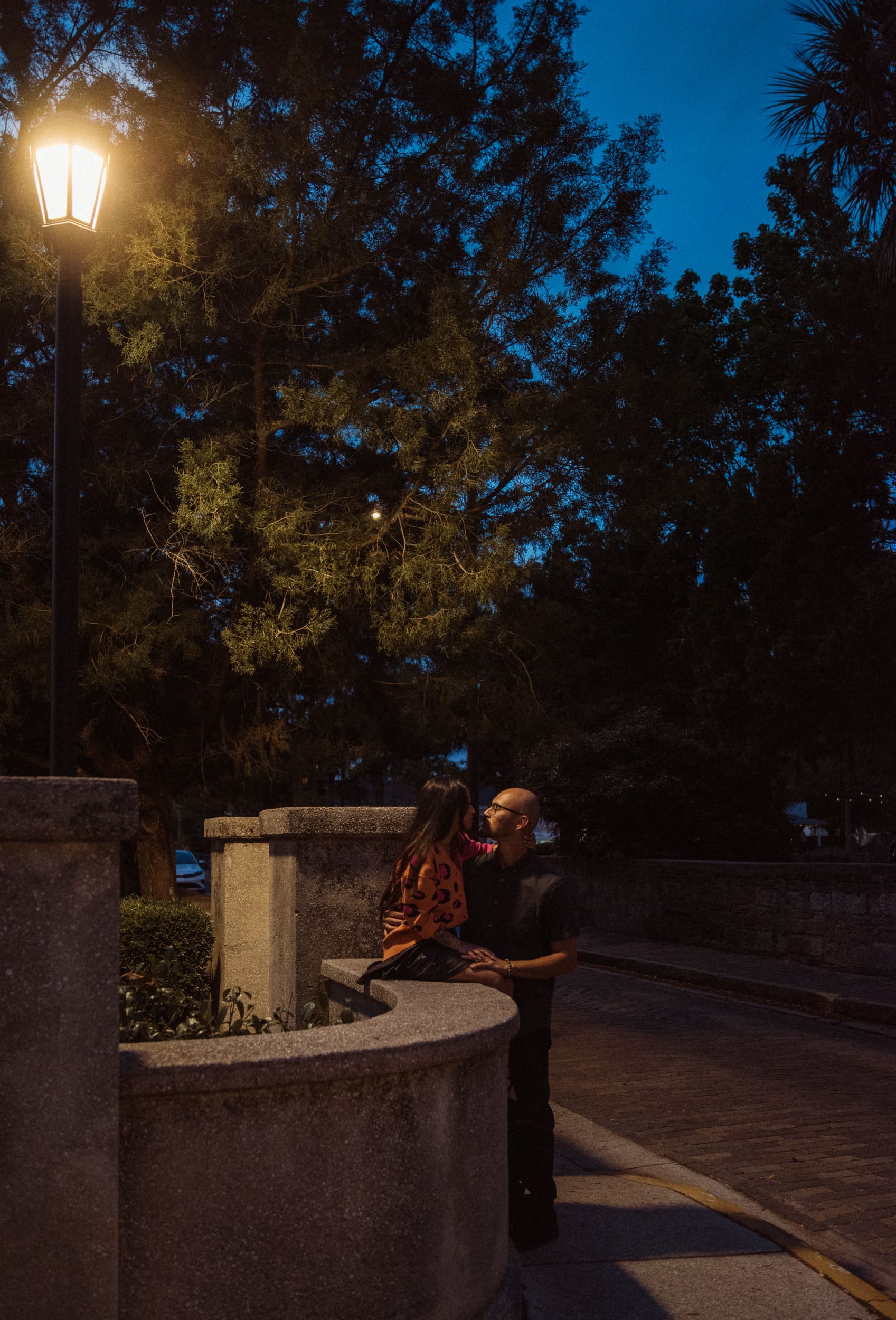Couple sitting on a stone bench as blue hour falls over downtown St. Augustine